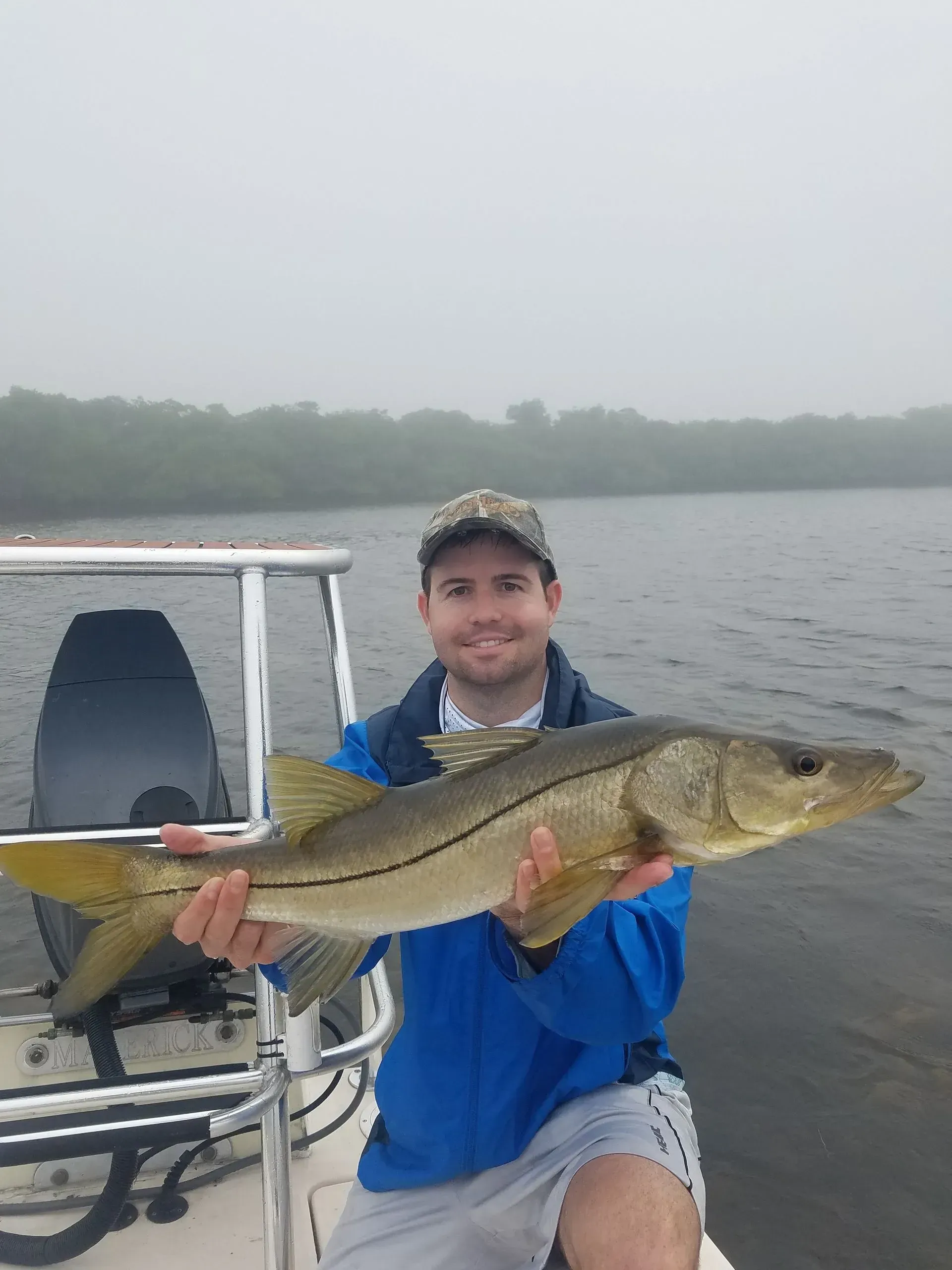A man on a boat is holding a large fish