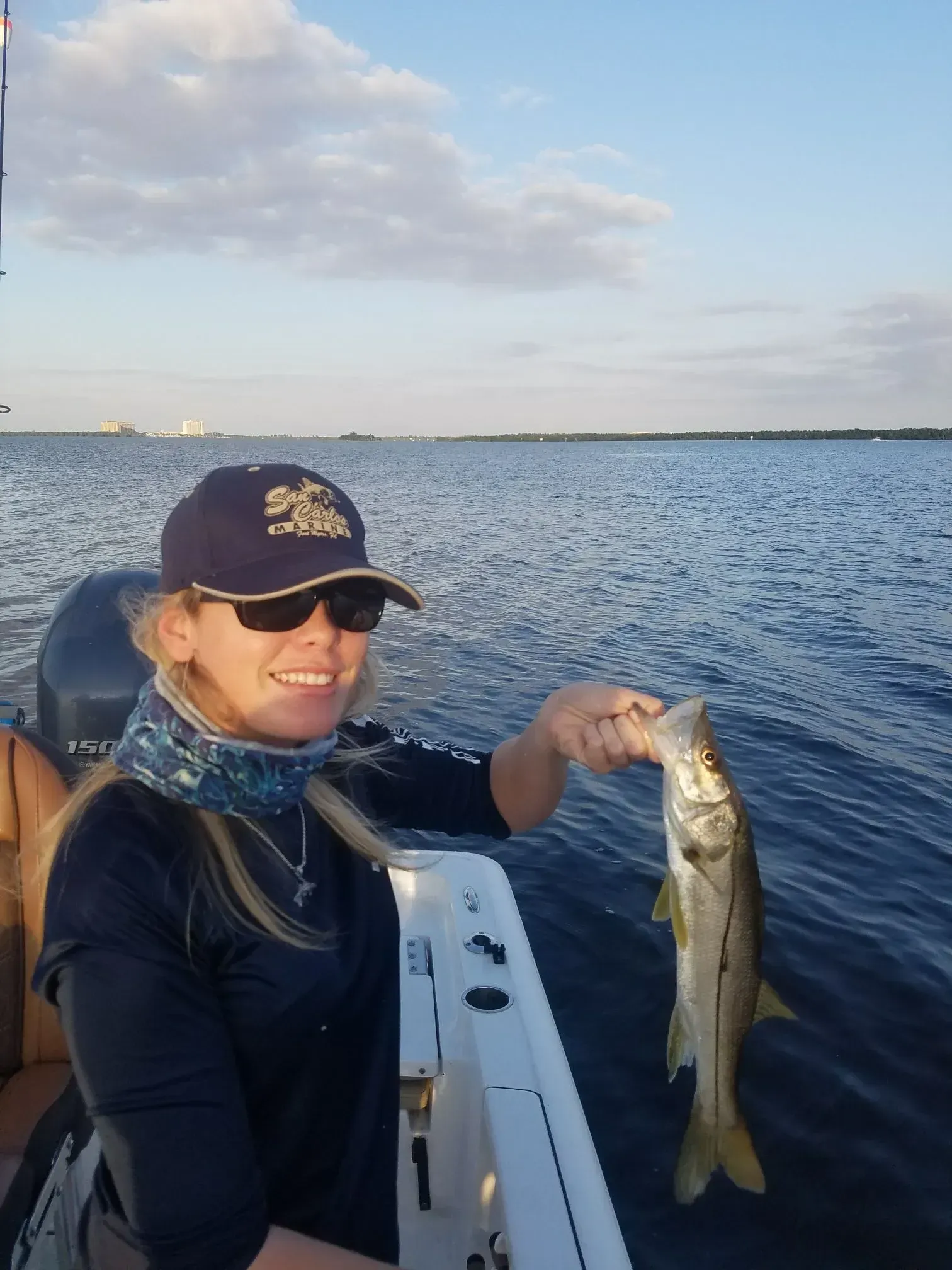 A woman is holding a fish on a boat in the water.