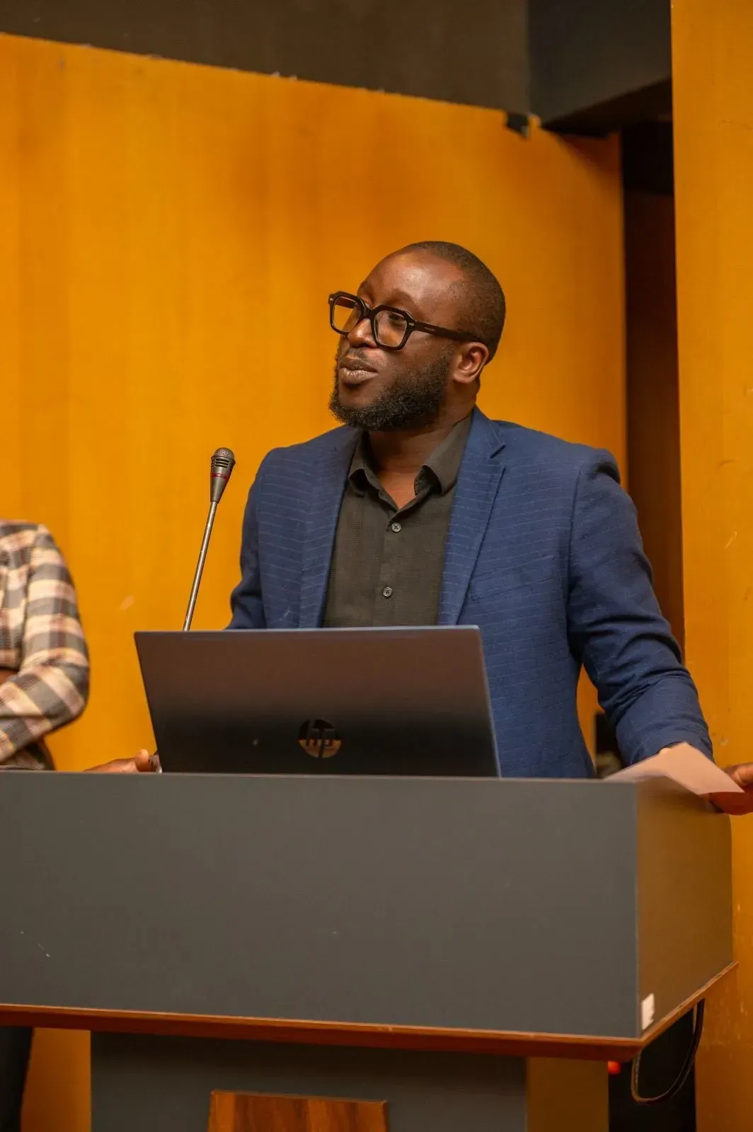 Un homme se tient debout sur un podium avec un ordinateur portable et un microphone.