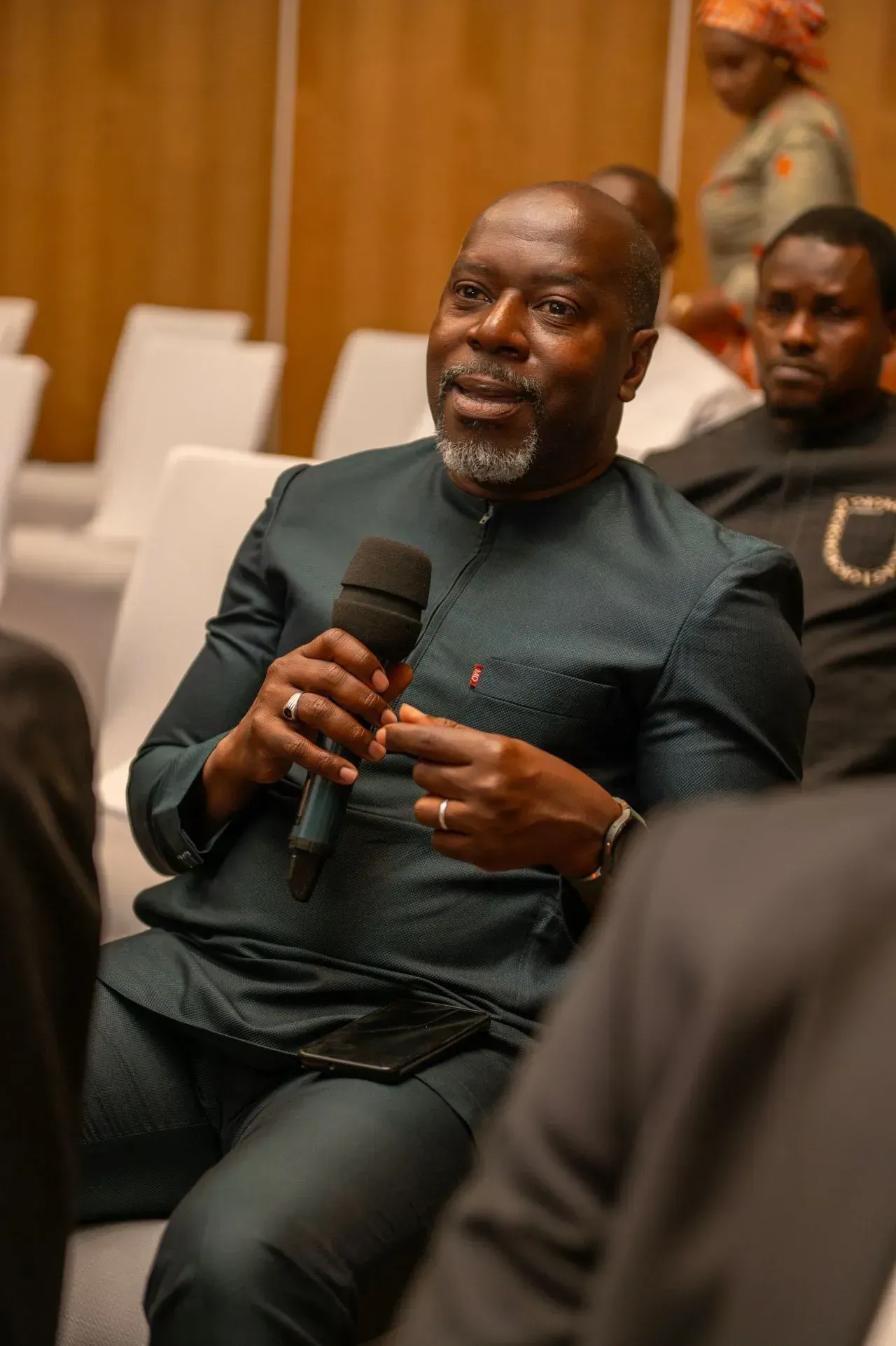 Un homme est assis sur une chaise et tient un microphone.