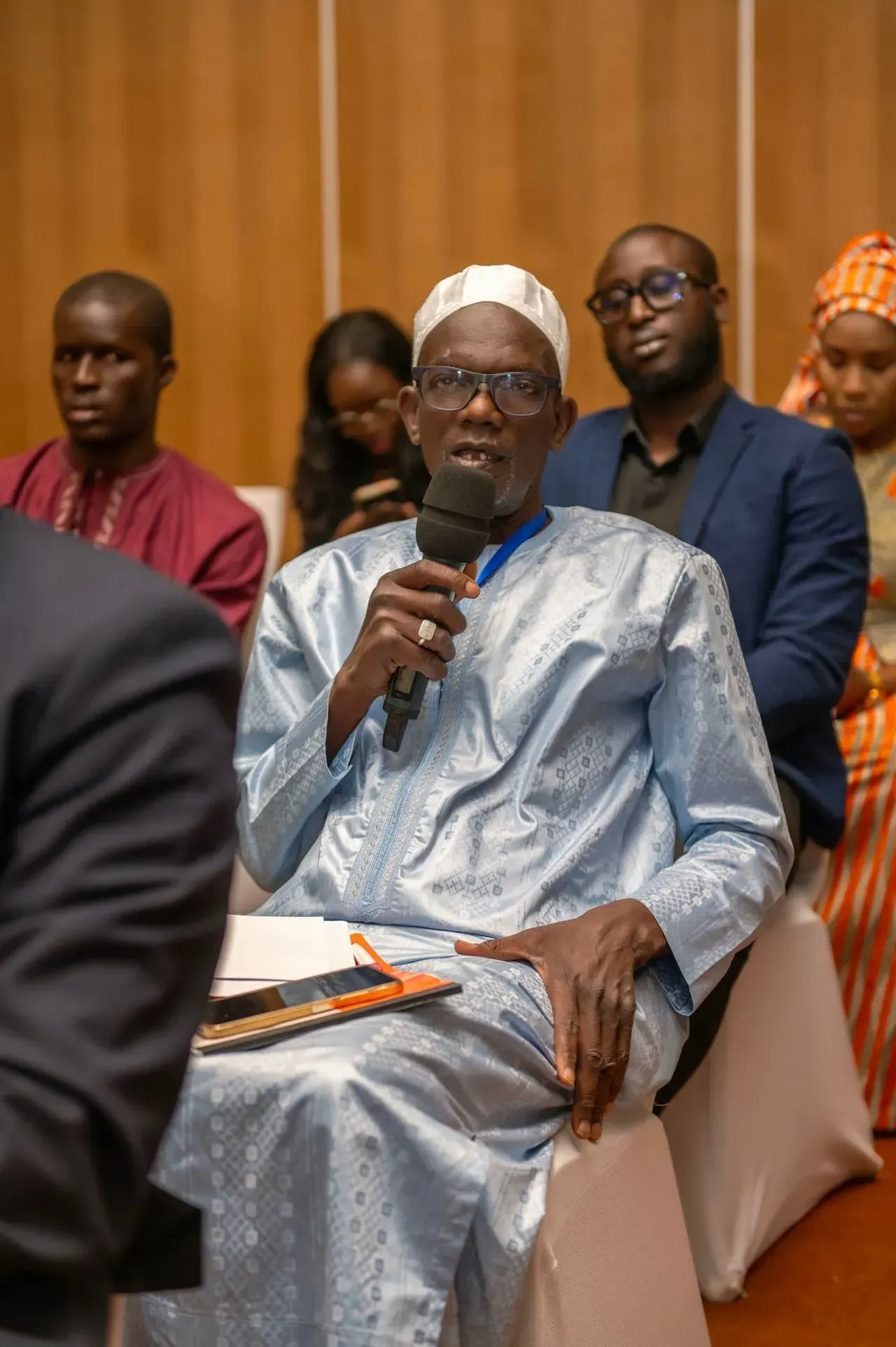Un homme est assis sur une chaise et tient un microphone.