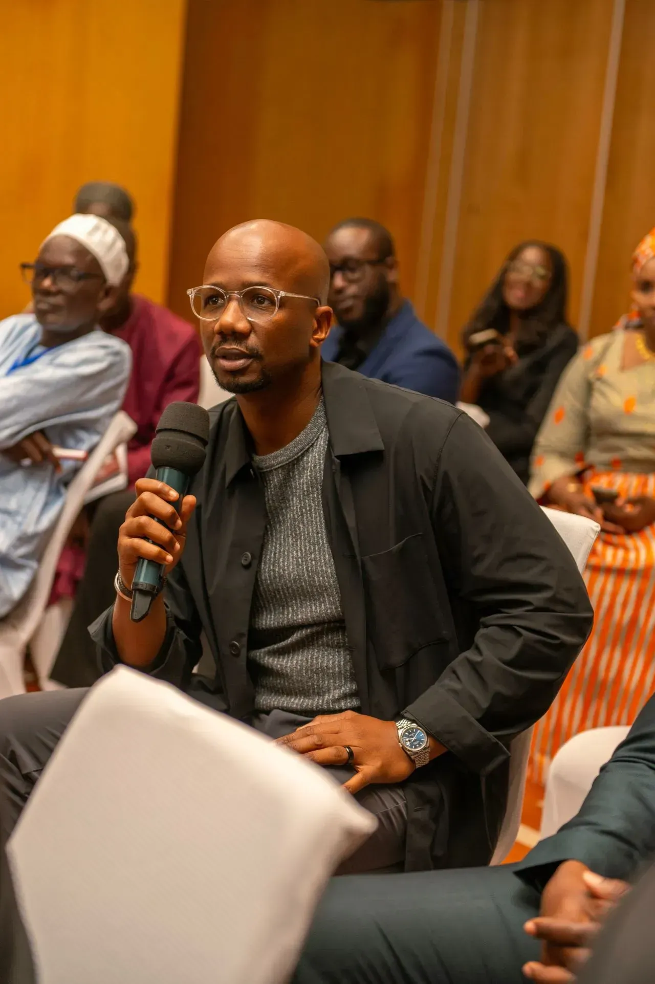Un homme est assis sur une chaise et tient un microphone.