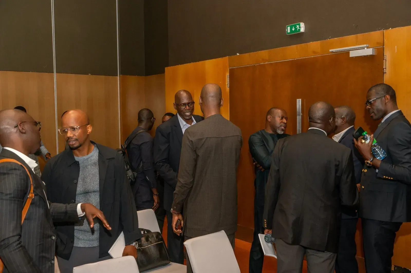 Un groupe d'hommes en costume se tiennent dans une pièce et discutent entre eux.