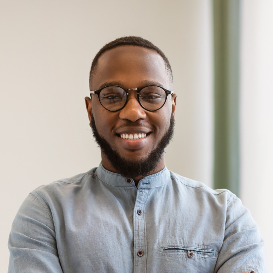 Un homme avec des lunettes et une barbe sourit à la caméra.