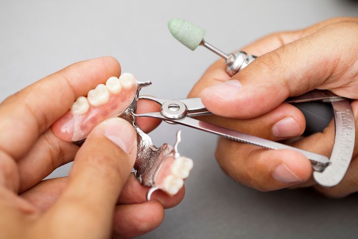 A woman is sitting in a dental chair looking at her teeth in a mirror