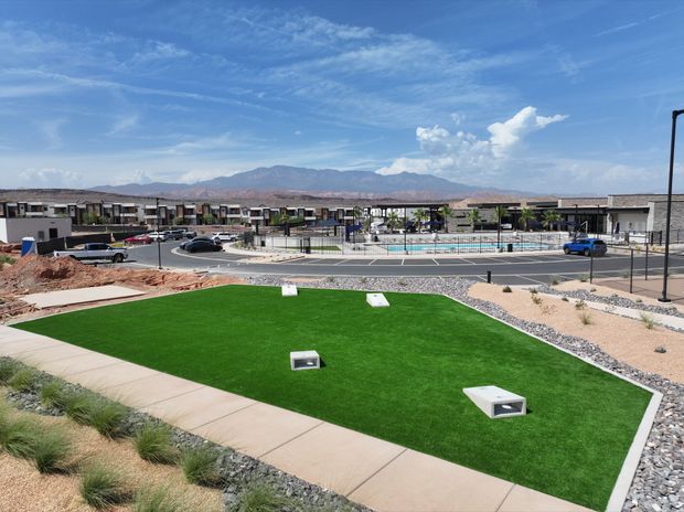 A large lawn with a pool in the background and mountains in the background.