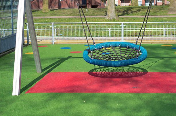 A blue nest swing is sitting on top of a red and green playground.