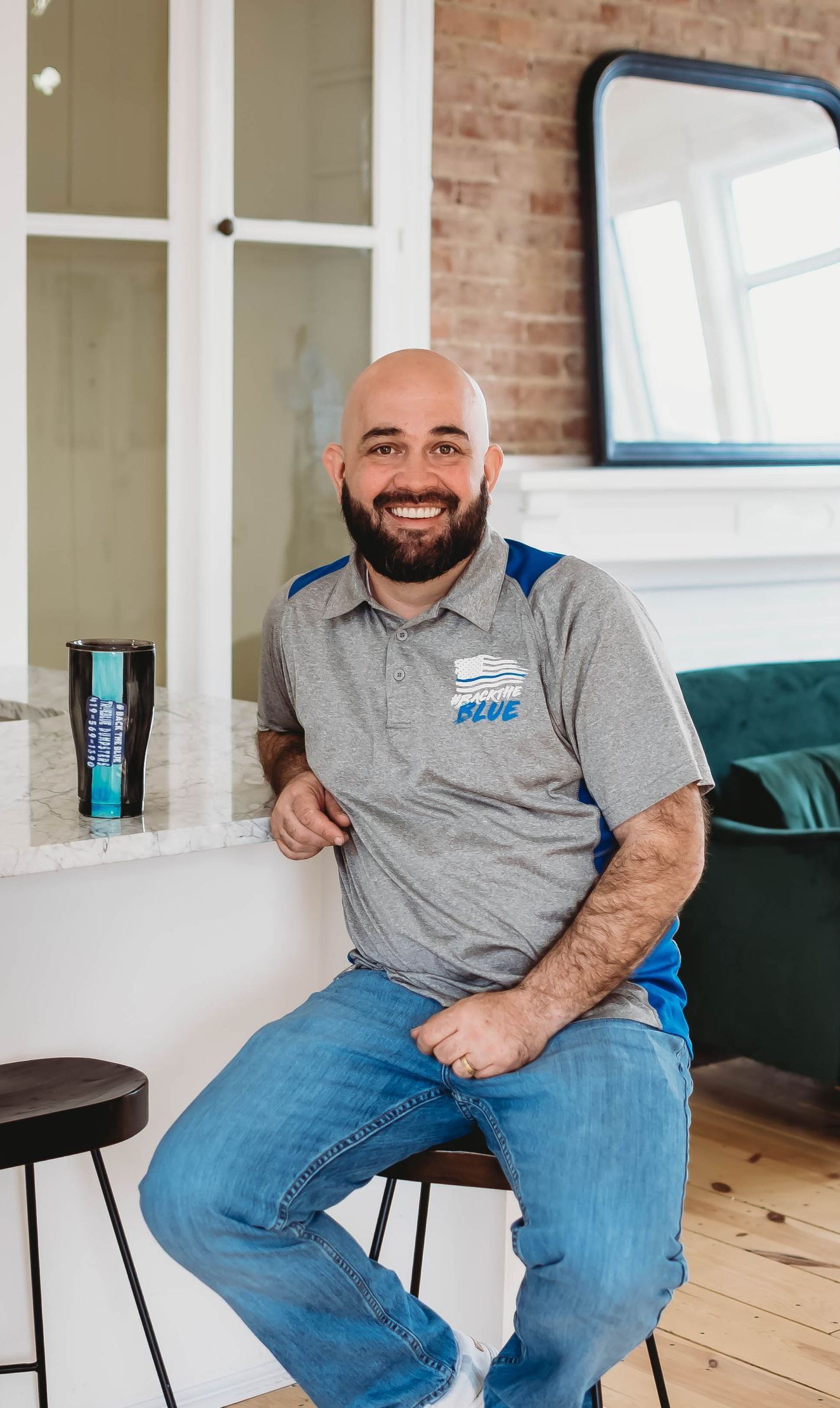 A man with a beard is sitting on a stool in a living room.