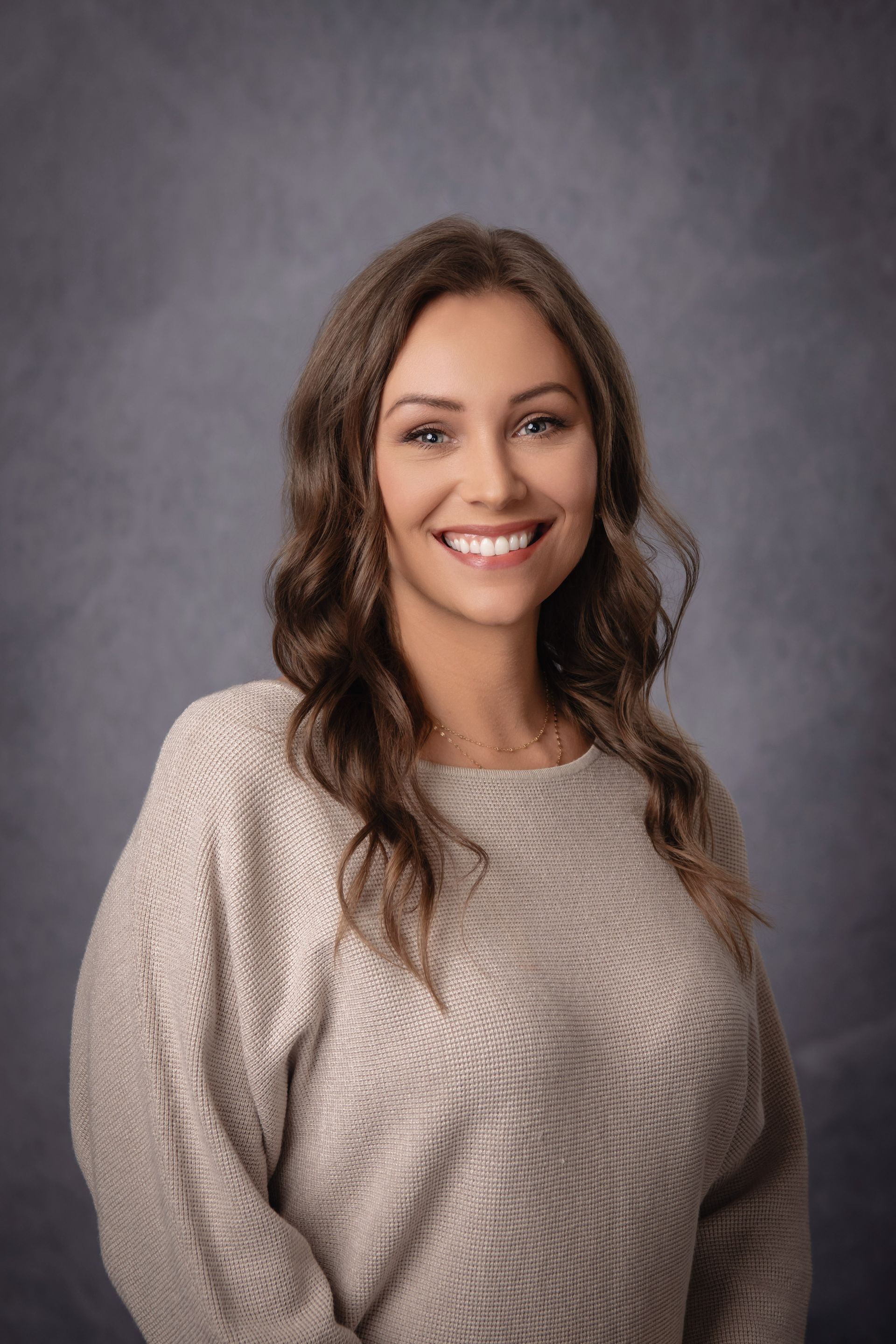The woman is wearing a sweater and smiling for the camera.