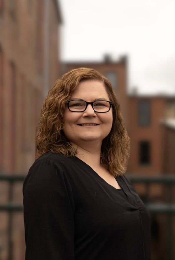 A woman wearing glasses and a black shirt is smiling for the camera.