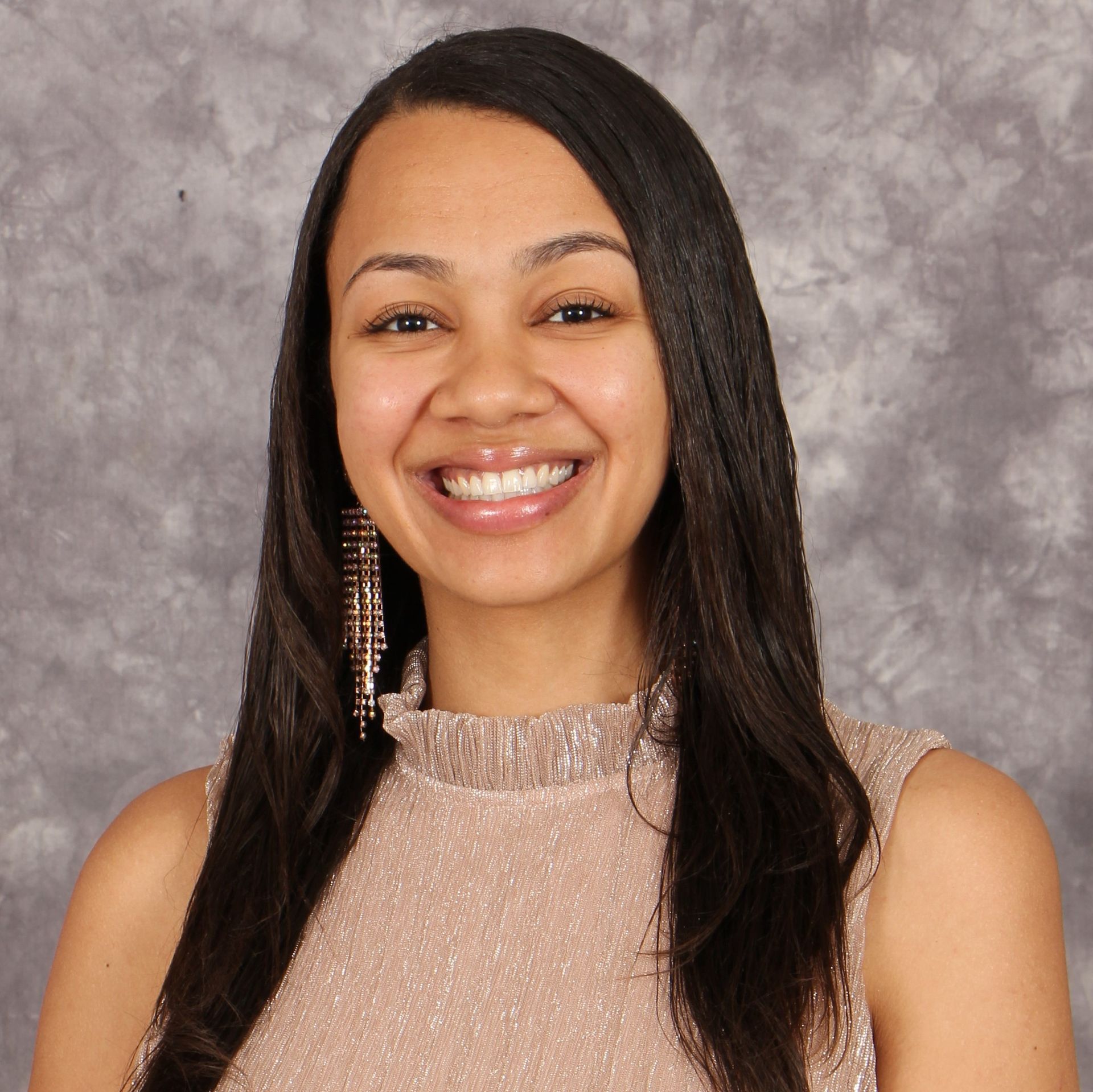 A woman with long hair is smiling and wearing earrings