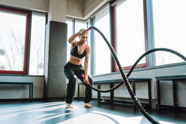 Woman with short hair exercising with battle ropes.