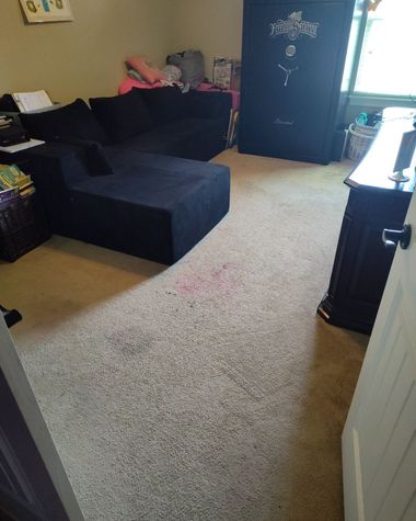 Small bedroom with a beige carpet, black sofa bed, and a dark wardrobe near a bright window.