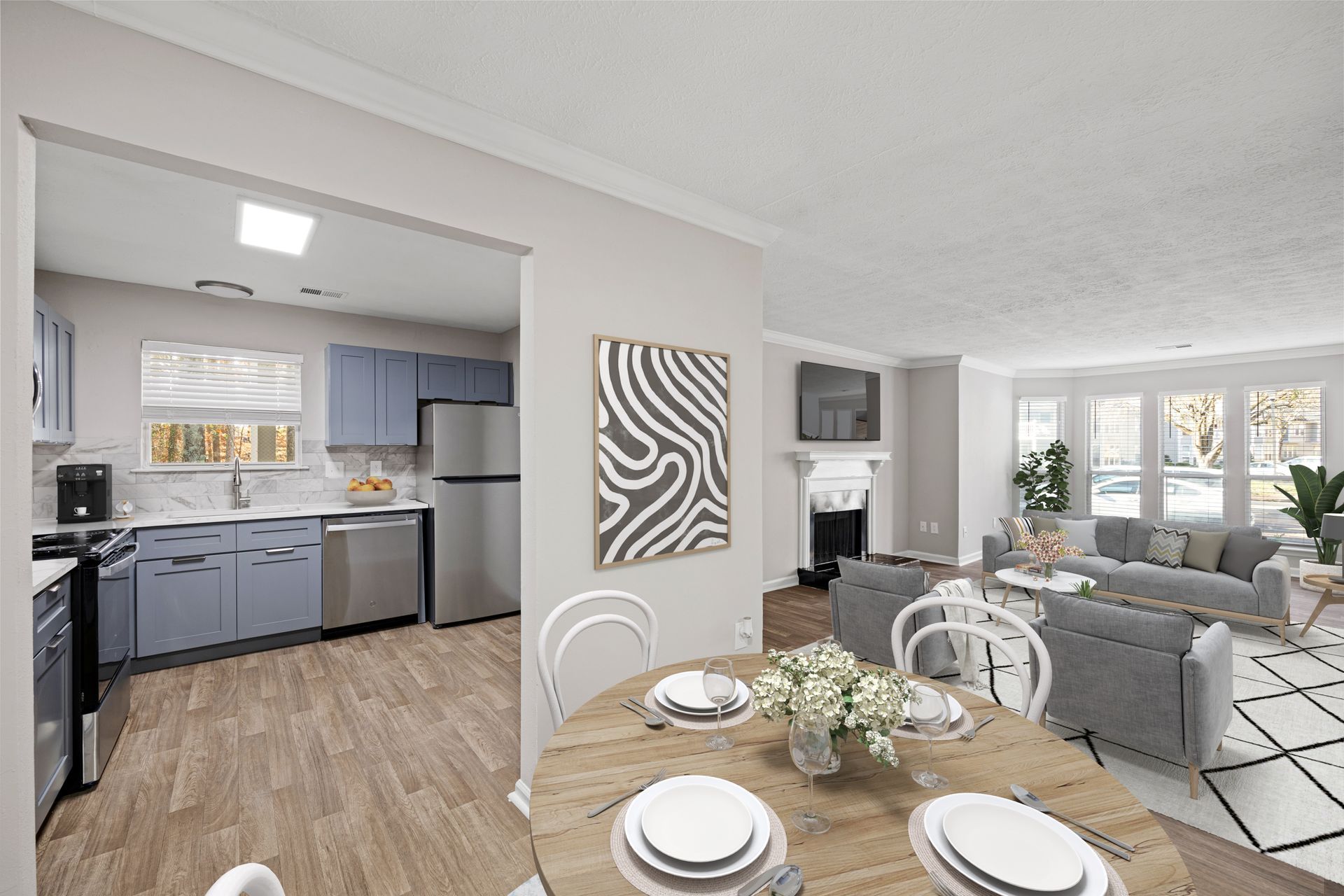 Dining area with round table set for a meal, opening to a kitchen and living room.