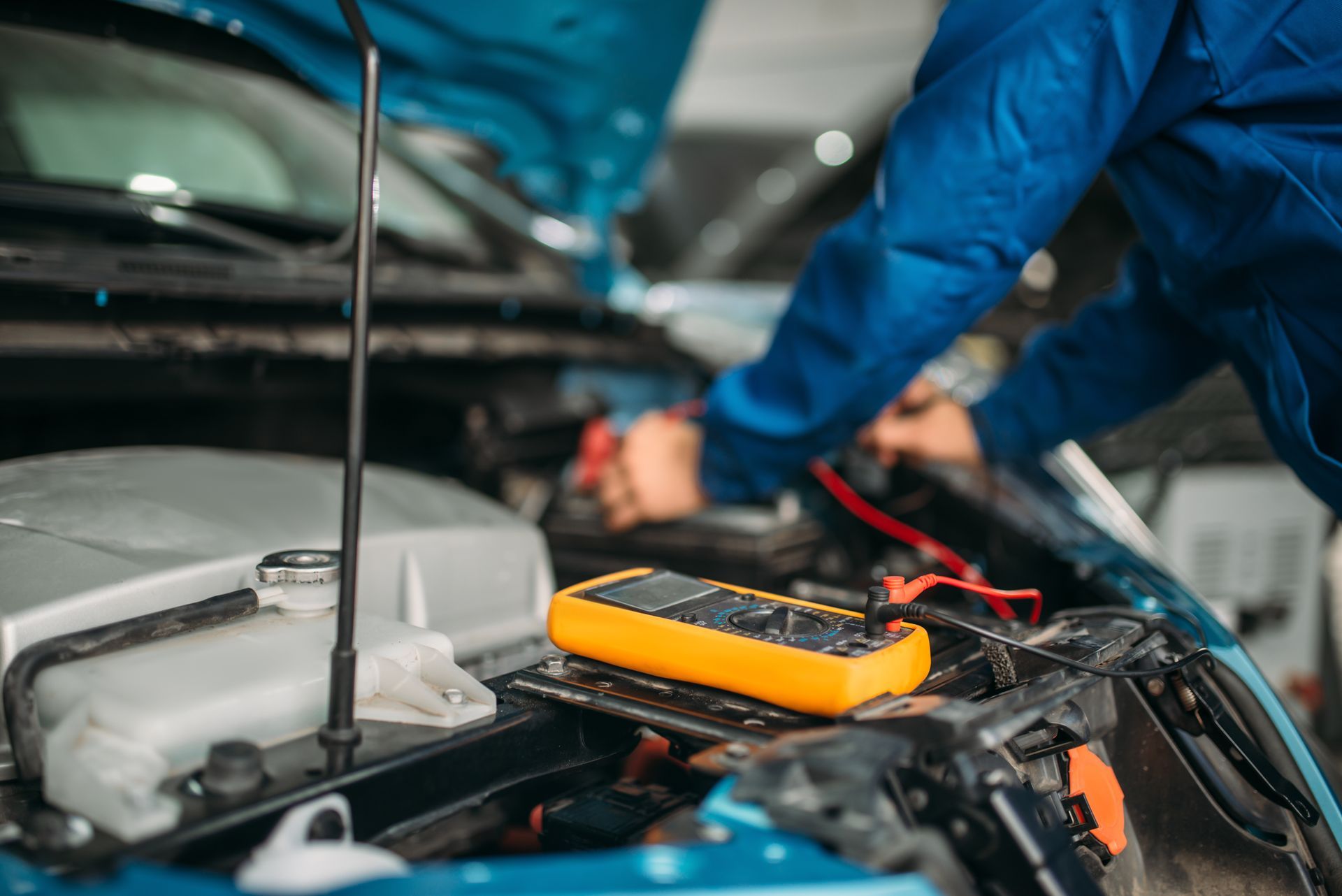 A mechanic is performing an auto electrician diagnostic on a car, checking the battery level. A mechanic is performing an auto electrician diagnostic on a car, checking the battery level.