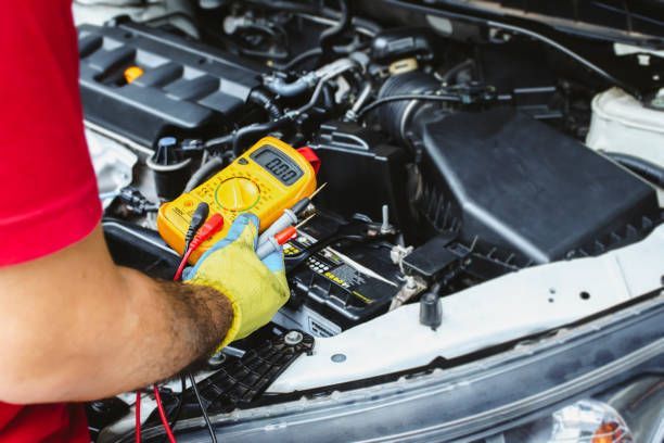 Mechanic testing car battery with multimeter for diagnostic auto electrical services under the hood