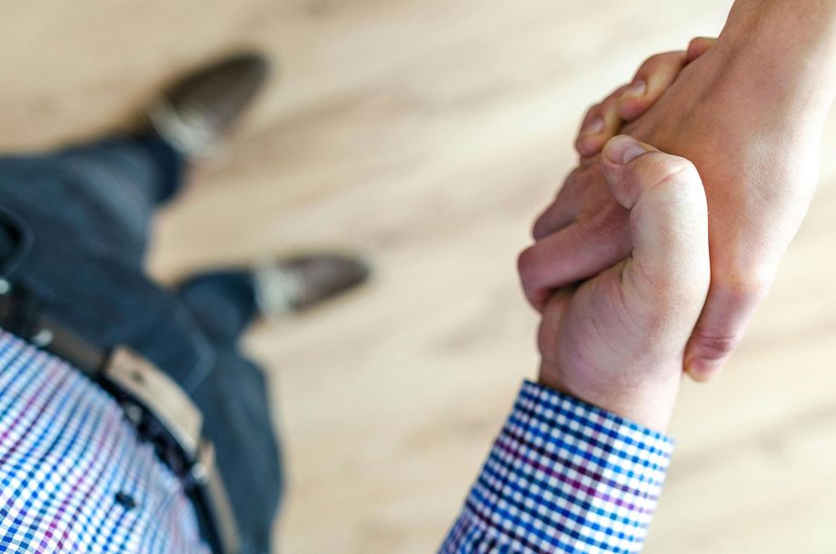 Two men are shaking hands on a wooden floor.