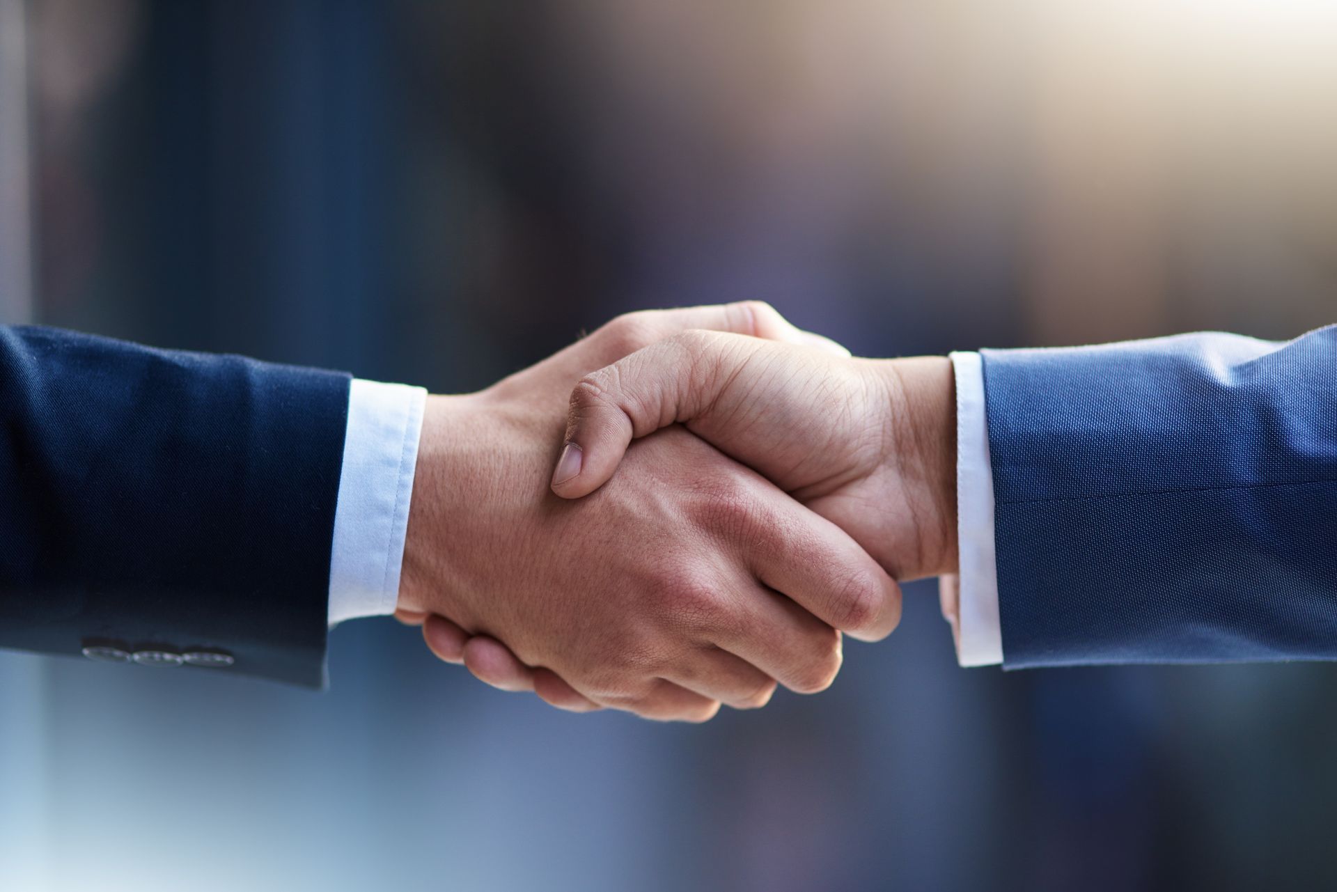 Two people in suits shaking hands, symbolizing a deal.