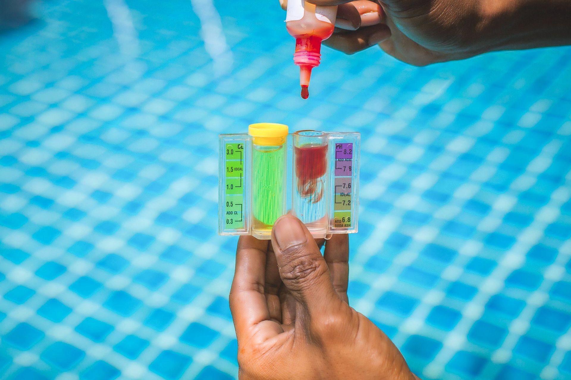A person is holding a test tube in front of a swimming pool.