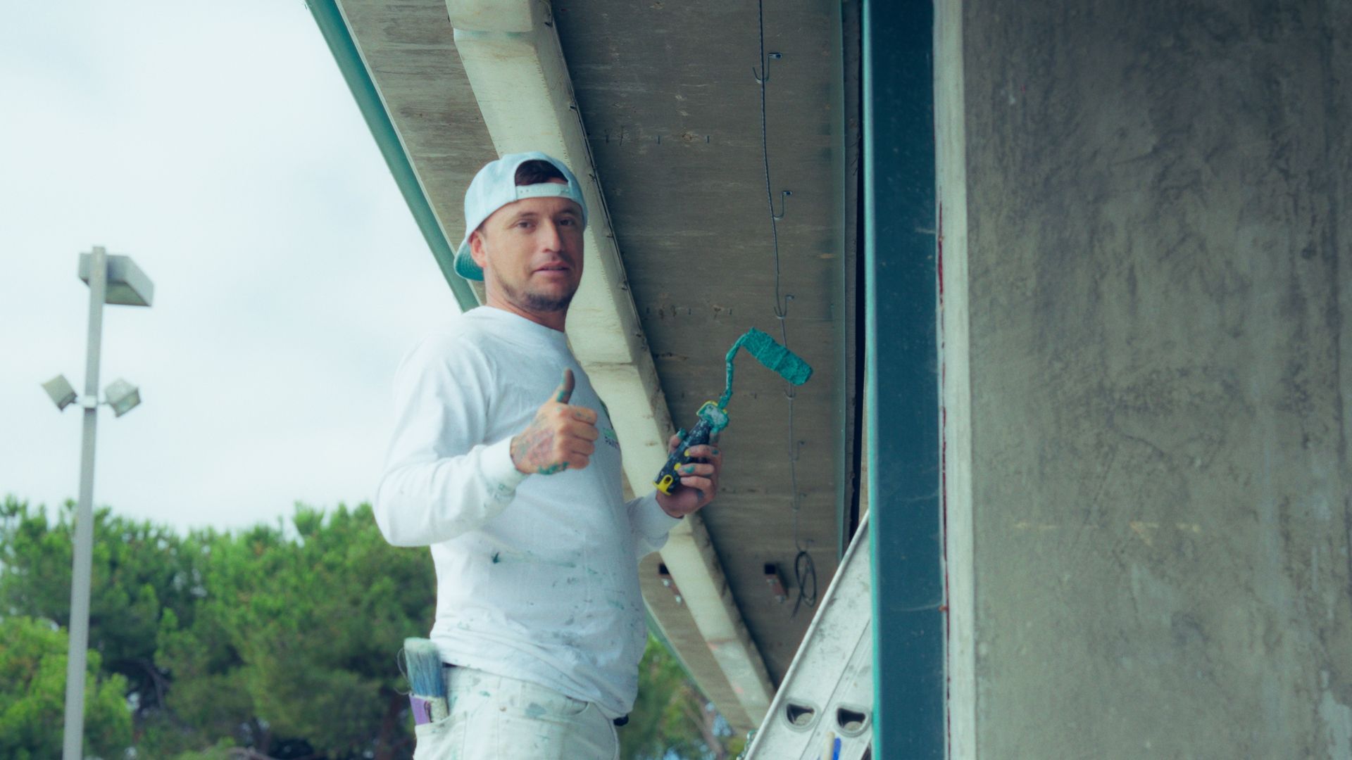 A man wearing a white shirt that says painting inc