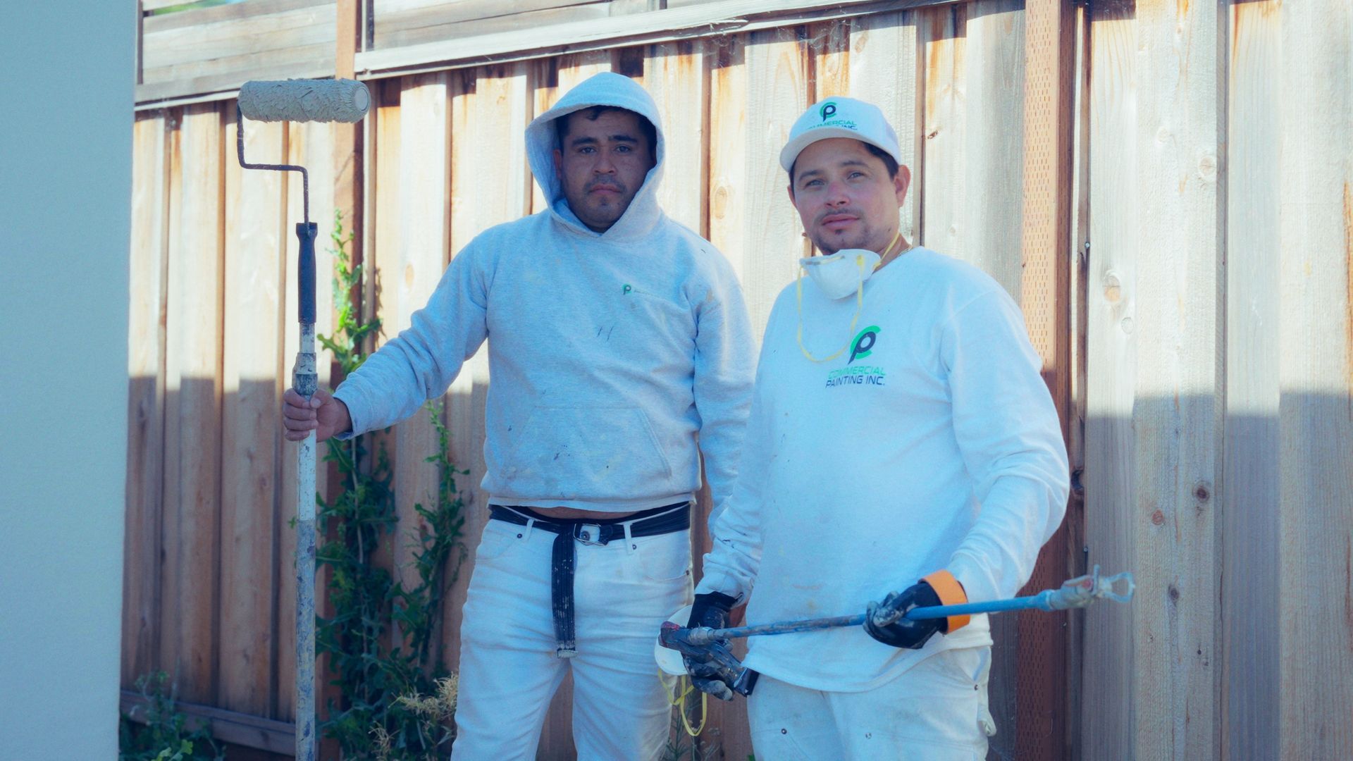 Two men are standing next to each other holding paint rollers.