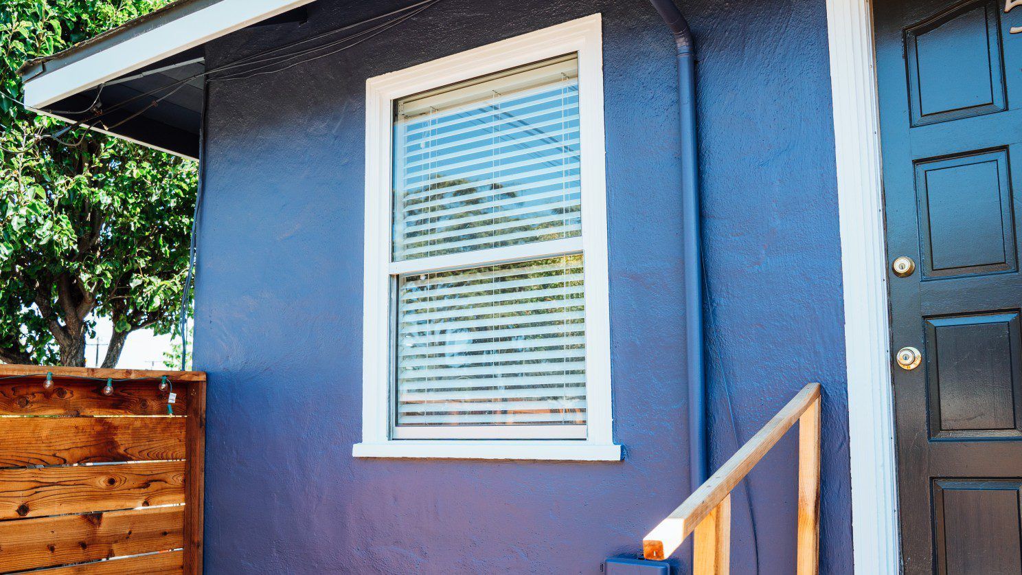 A blue house with a black door and stairs leading up to it.
