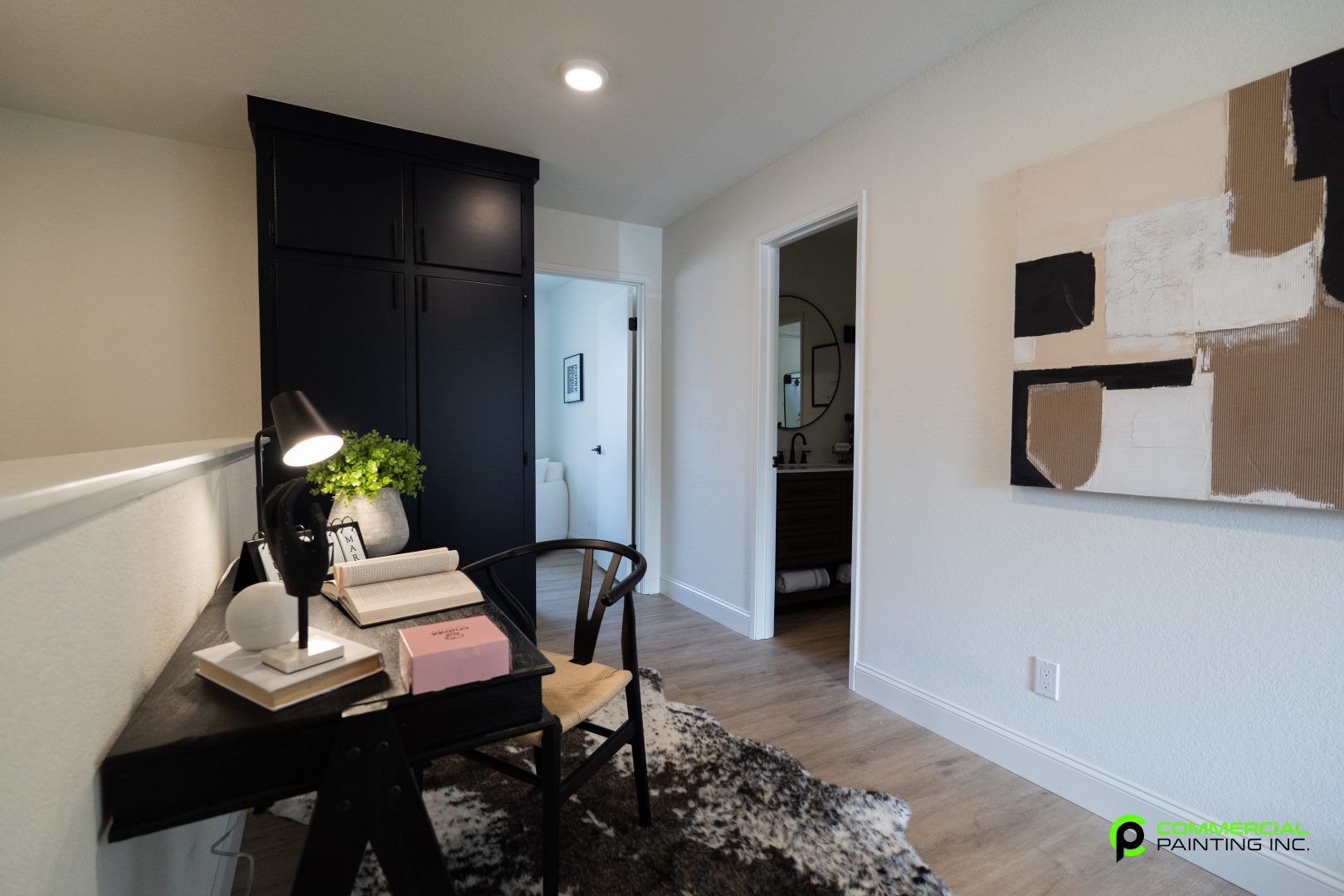 A room with a desk and chair in it and a painting on the wall.
