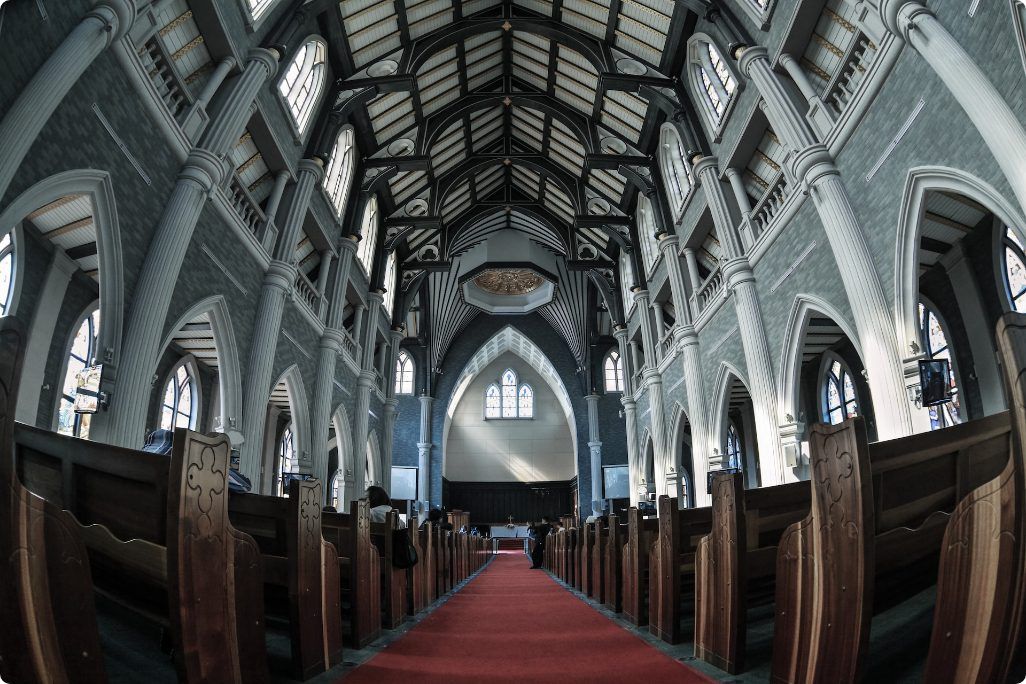 The inside of a church with a red carpet between the pews.