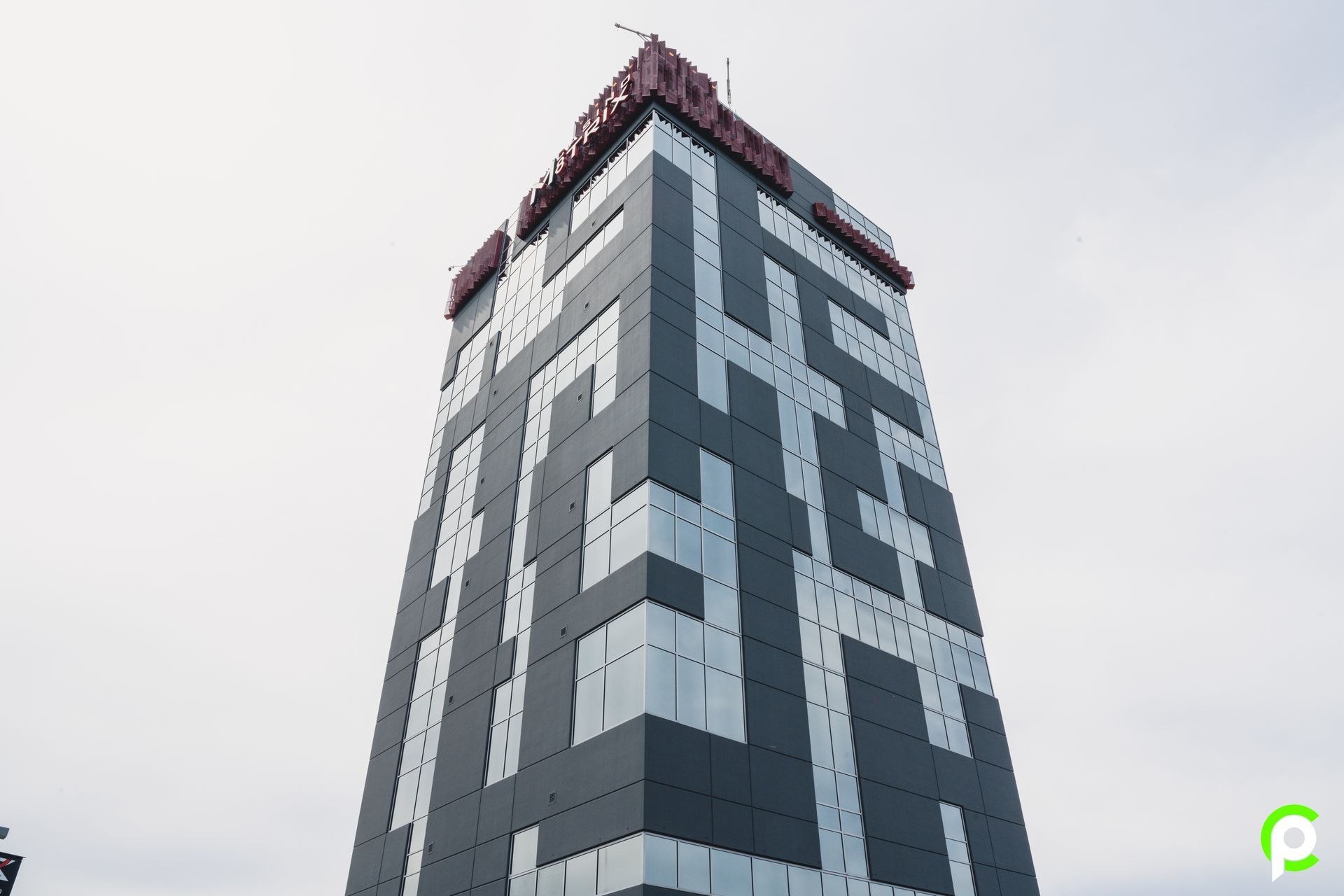 Tall building with a maze-like design, black and silver panels against a cloudy sky.