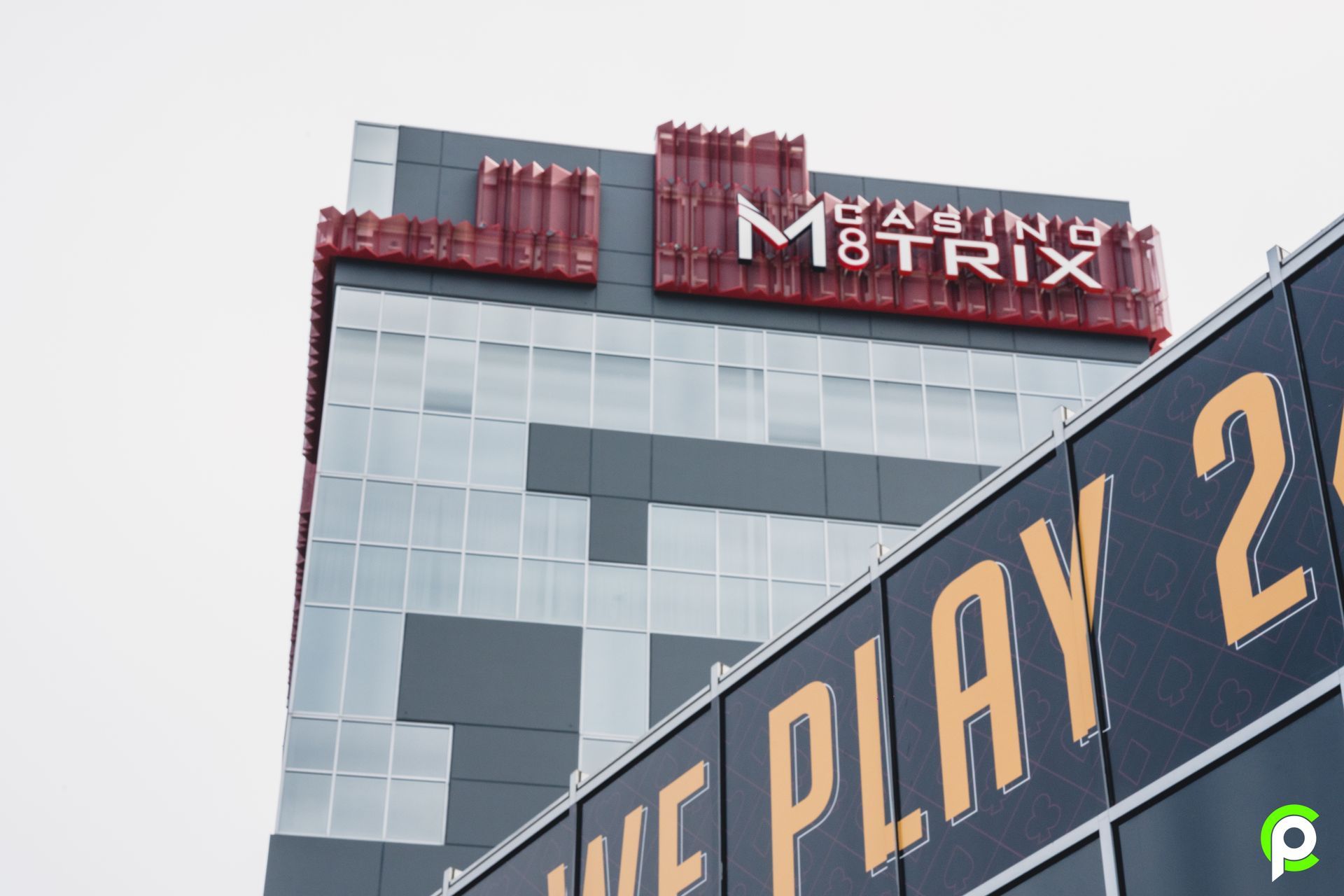 Building exterior with a large "M8TRIX" sign.  The building has a pixelated design, with a partial sign that says "WE PLAY 2".