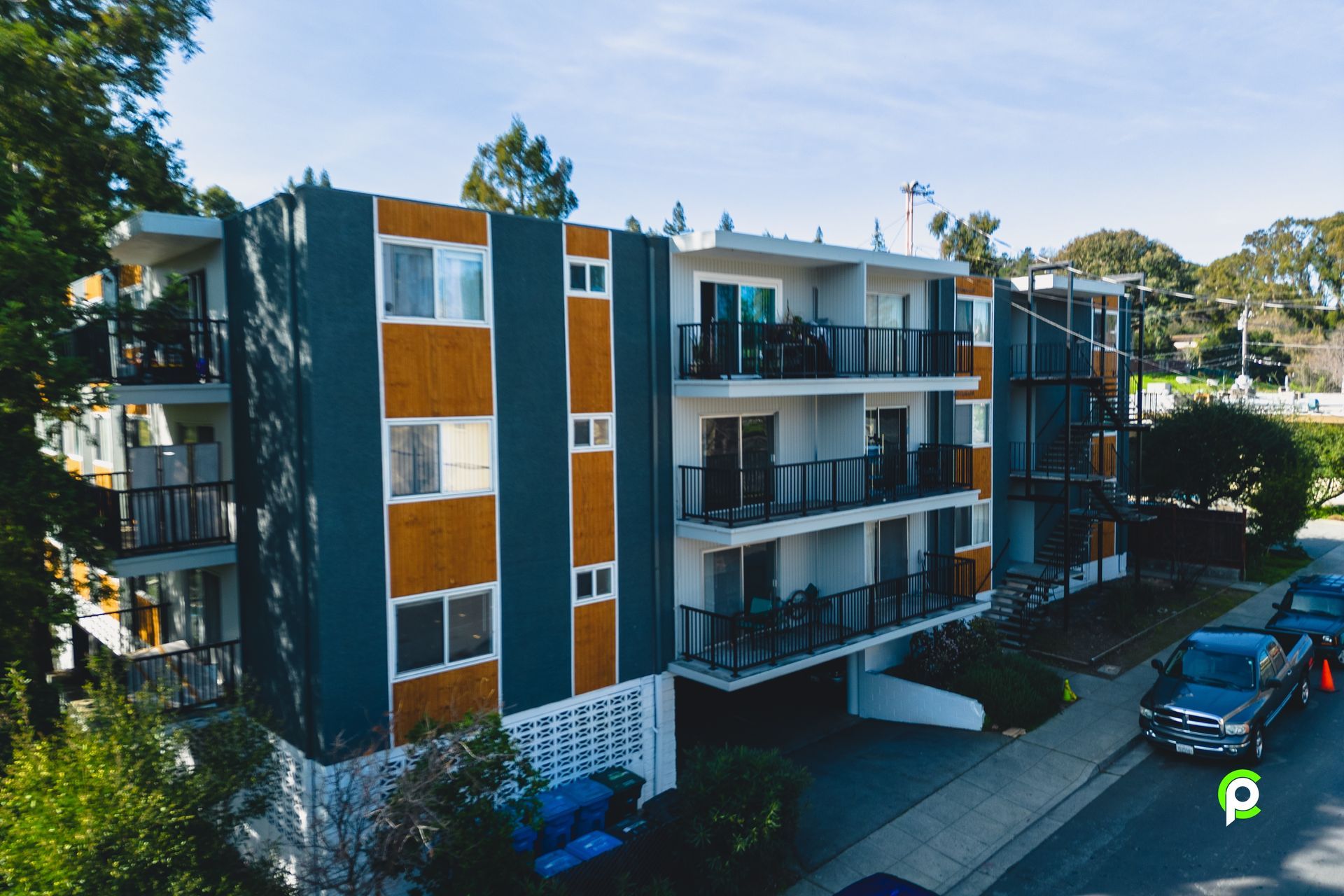 An aerial view of a large apartment building with cars parked in front of it
