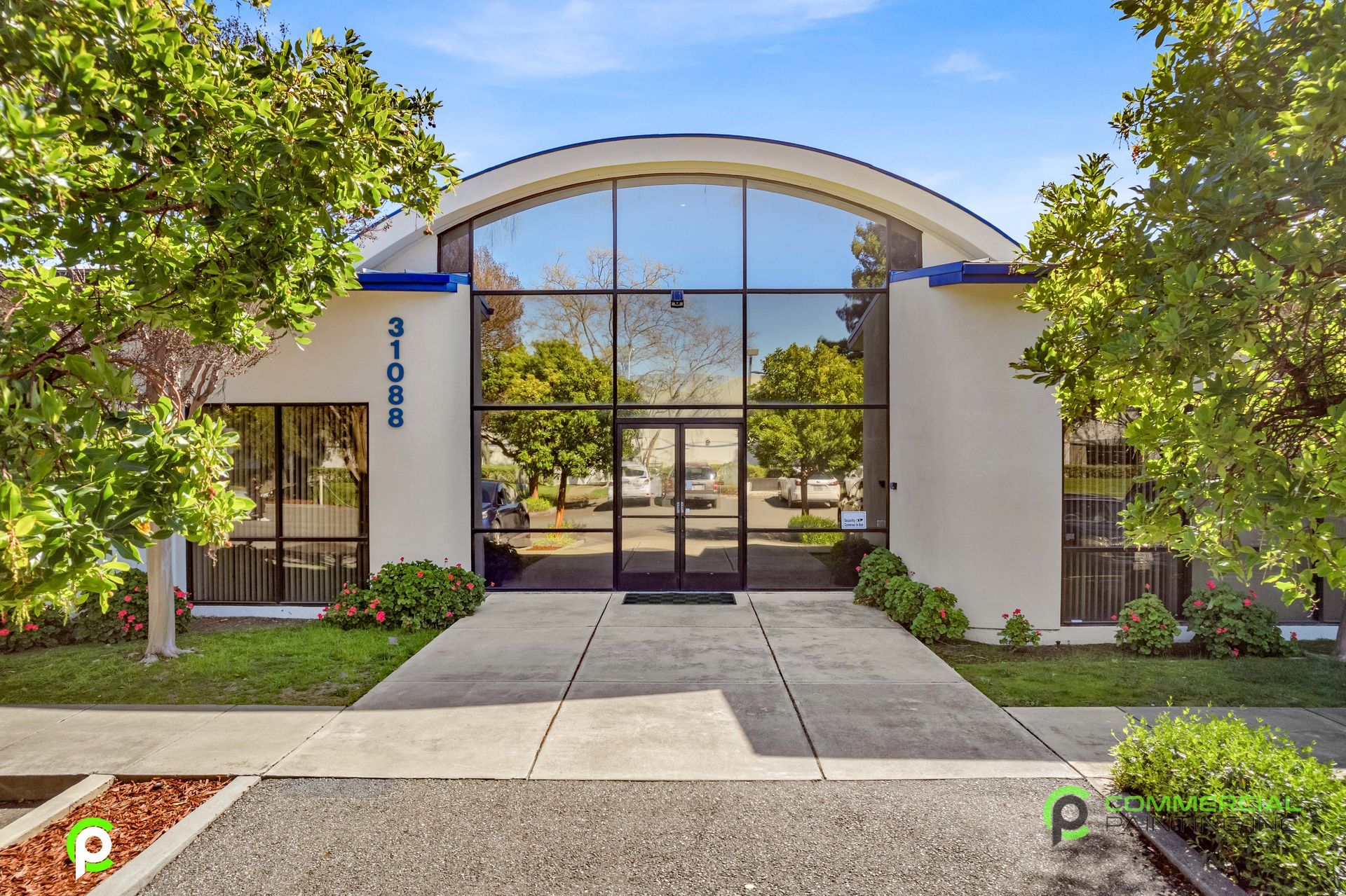 A white building with a curved roof and trees in front of it