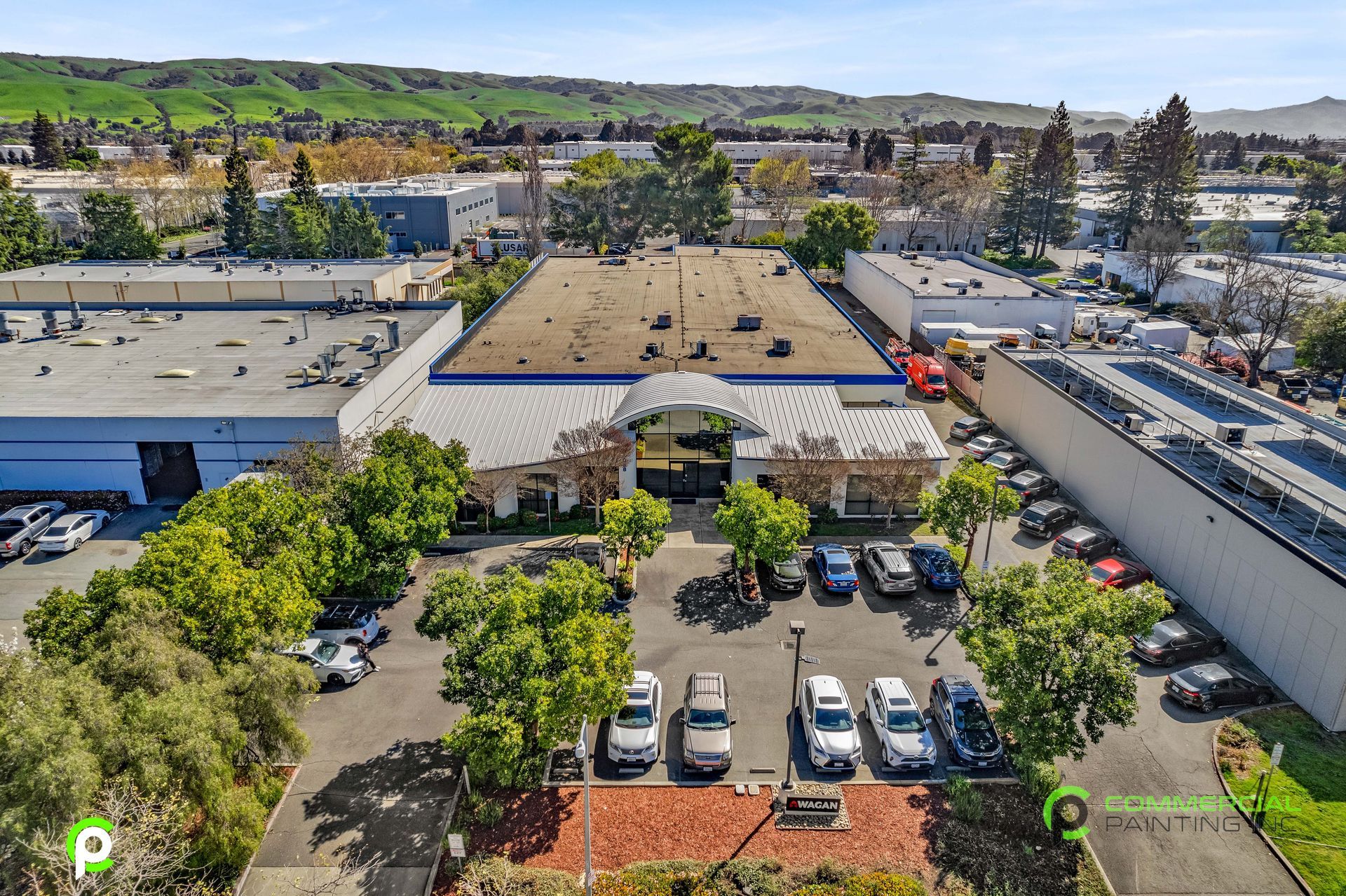 An aerial view of a parking lot with cars parked in front of a large building.