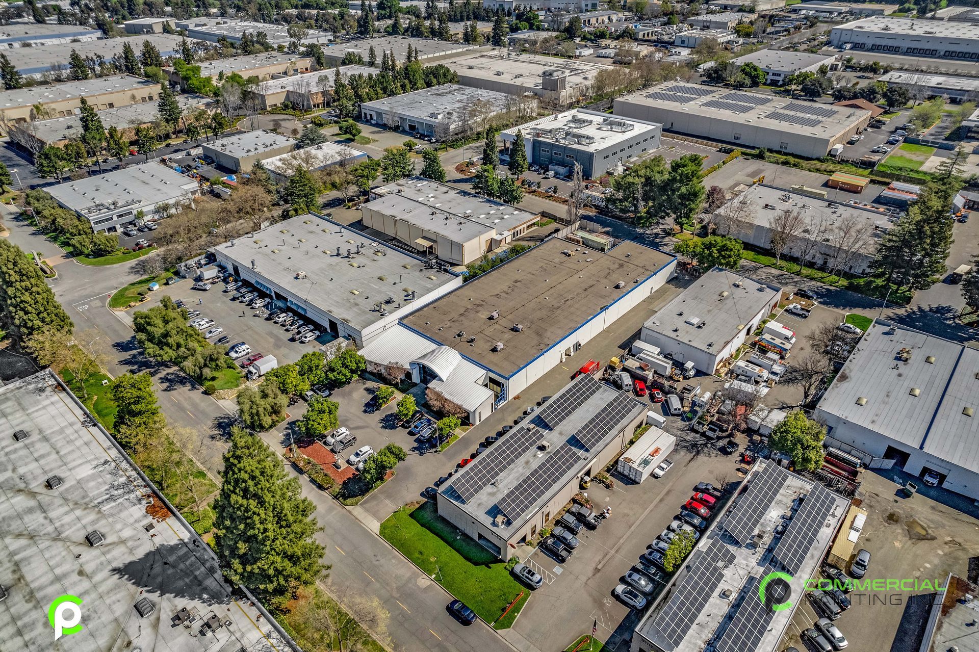 An aerial view of a large industrial area with lots of buildings and solar panels on the roofs.