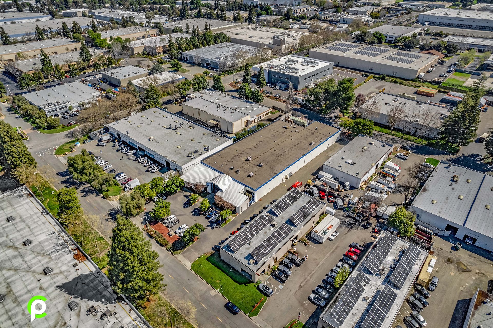 An aerial view of a large industrial area with lots of buildings and solar panels on the roofs.