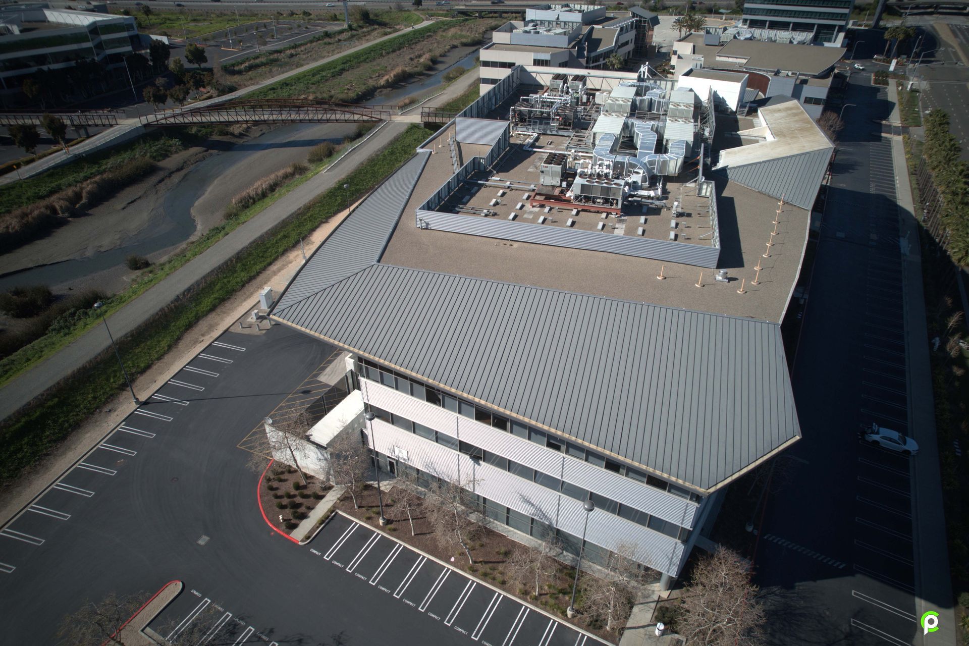 An aerial view of a large building with a parking lot in front of it.