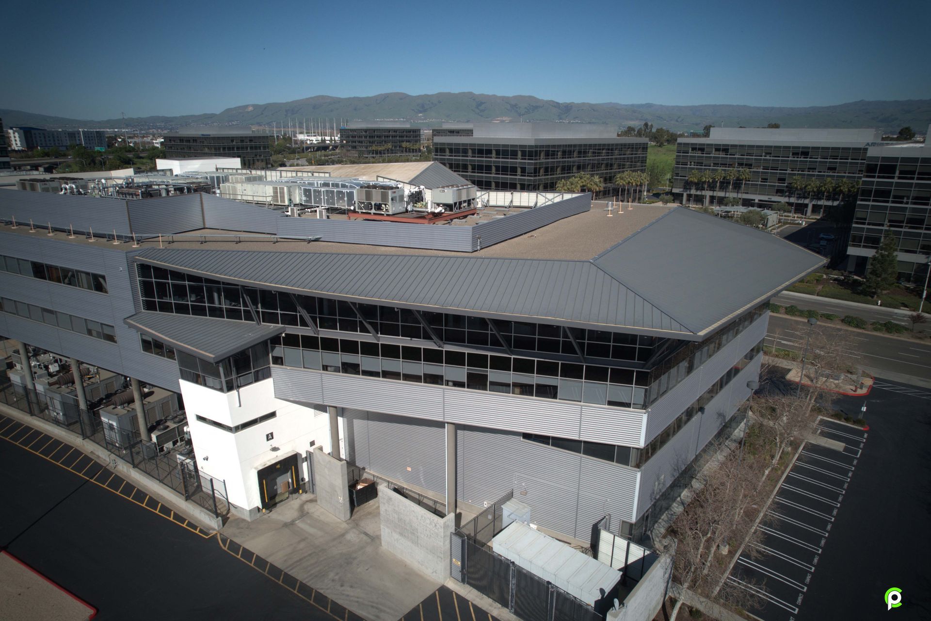 An aerial view of a large building with a parking lot in front of it.