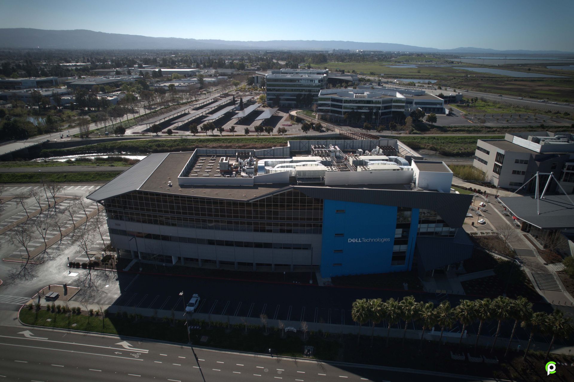An aerial view of a large building with a blue roof in a city.