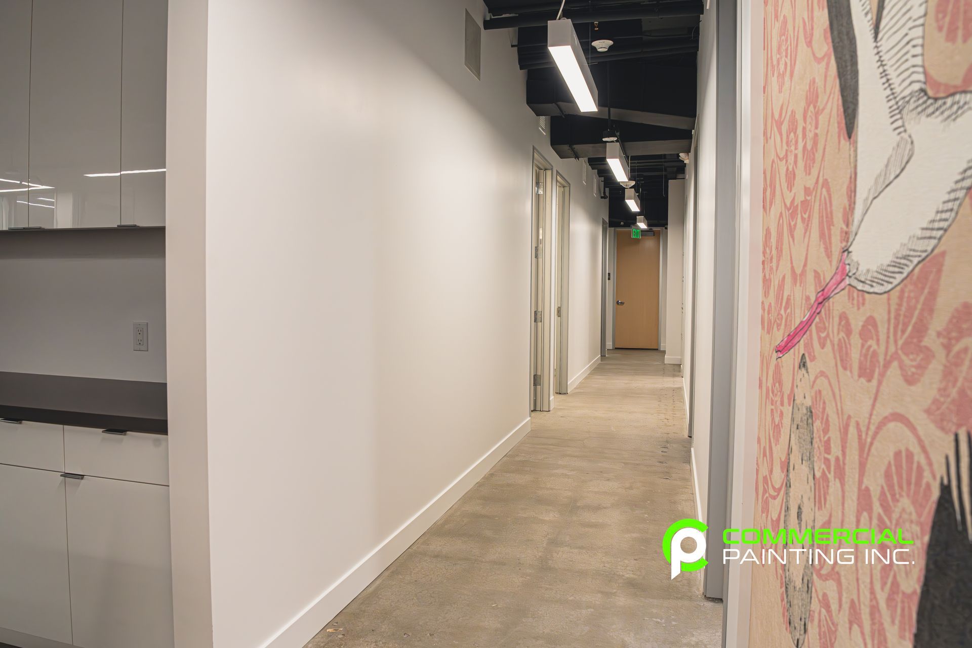 A long hallway with white walls and a painting on the wall.