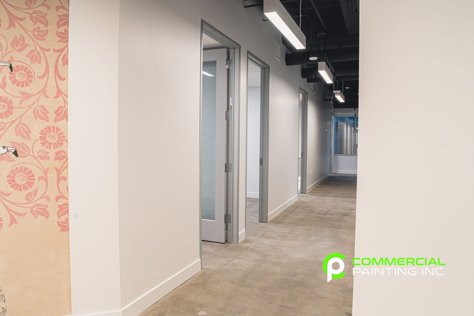 A long hallway with white walls and carpeted floors in an office building.