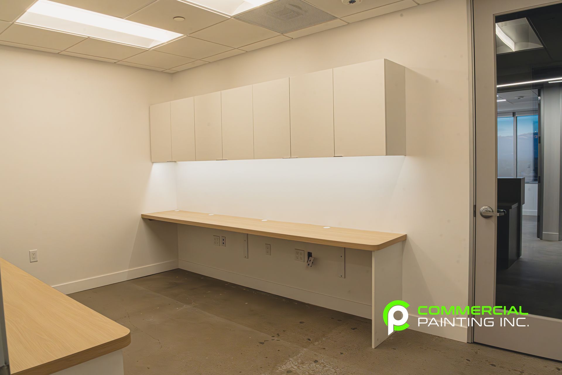 An empty office with a wooden desk and cabinets.