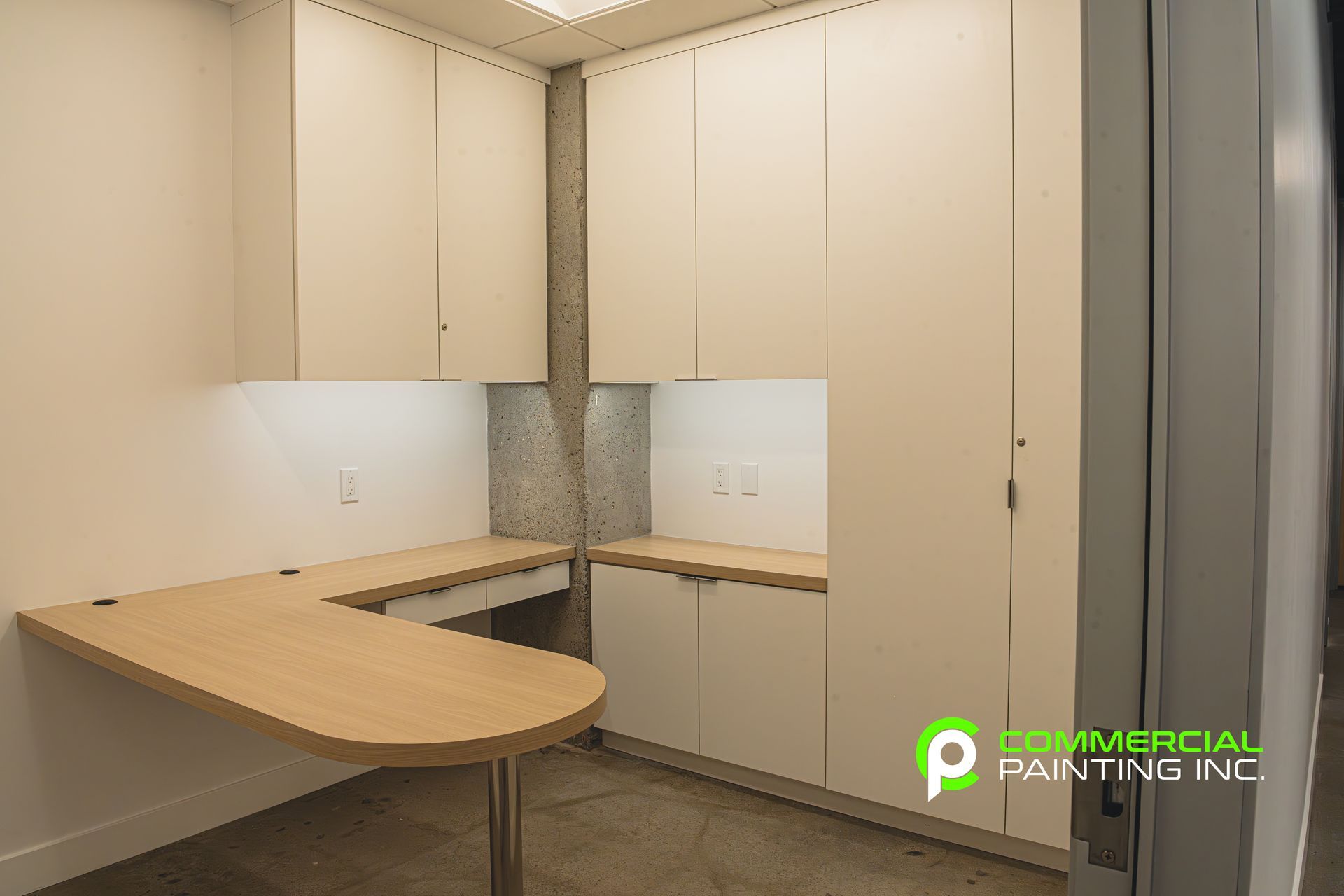 A room with white cabinets and a wooden desk.