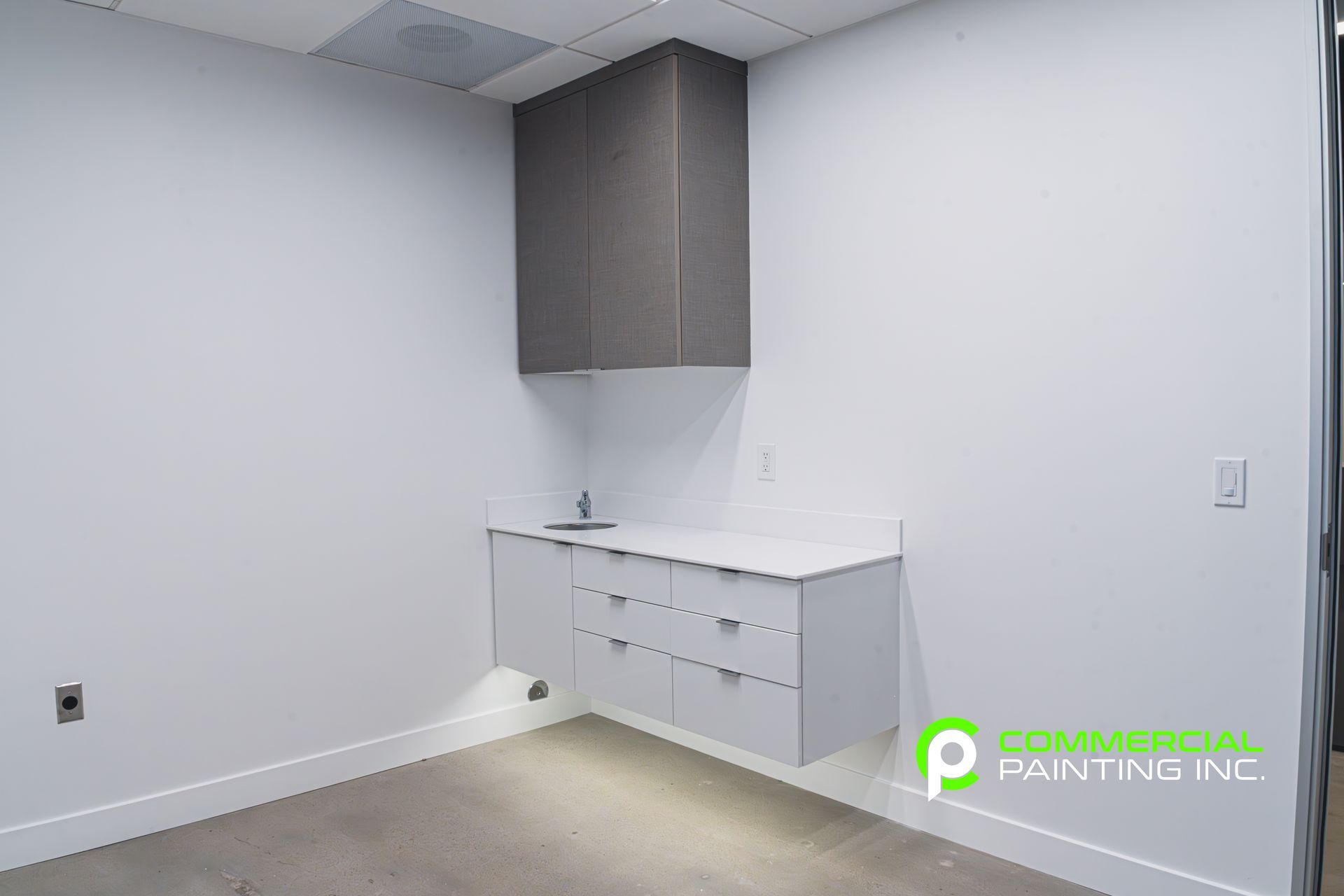 An empty room with white cabinets and a sink.