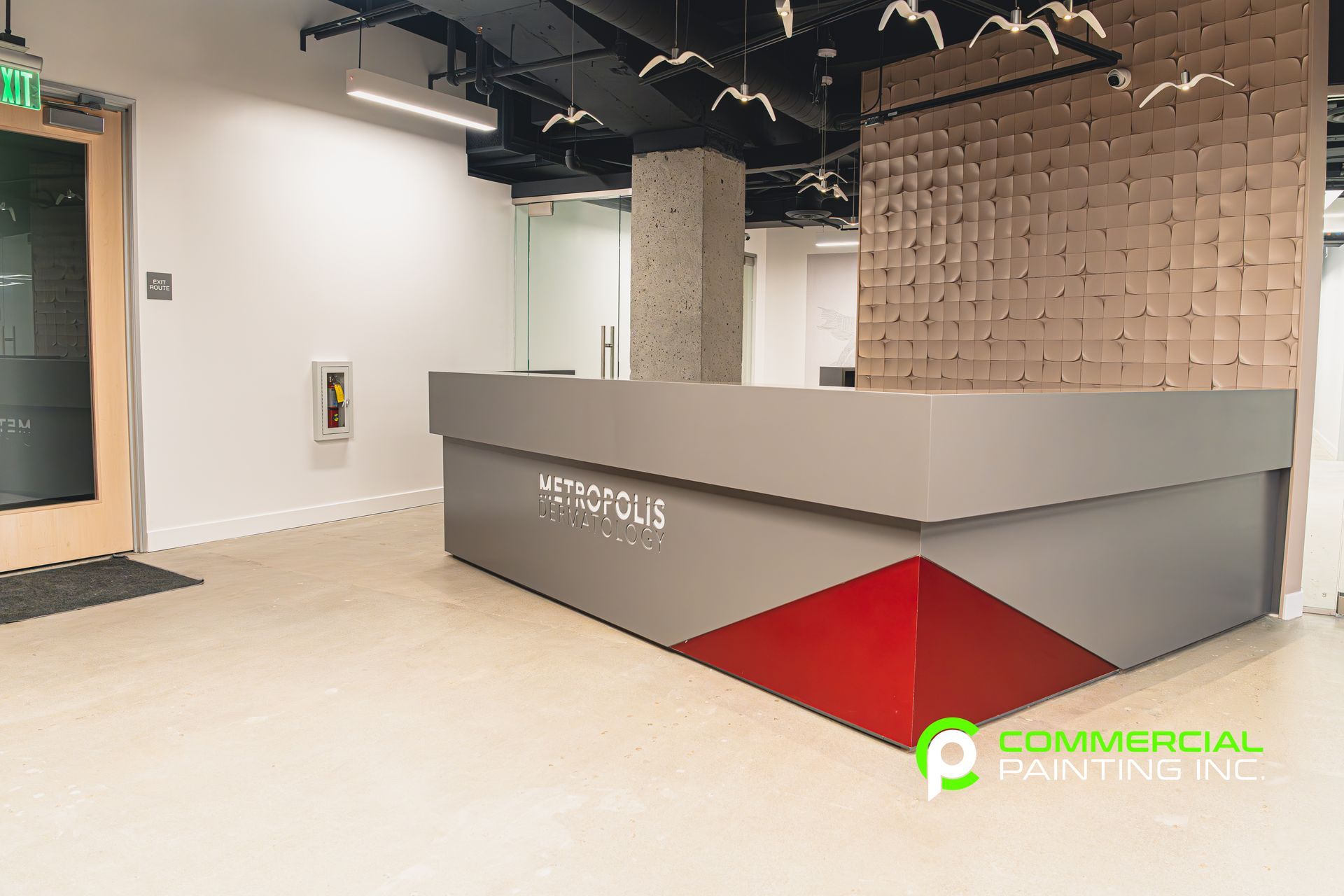 A large gray and red reception desk in a room with a brick wall.
