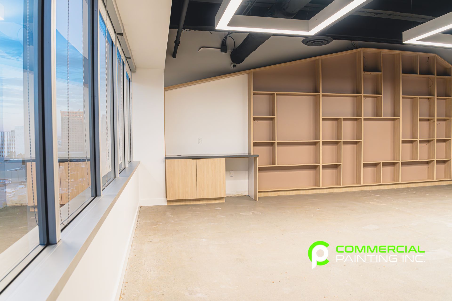 A large empty room with a lot of shelves and windows.