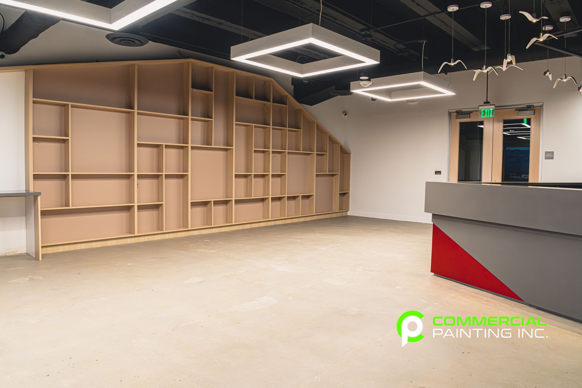 An empty room with shelves and a red and gray counter.