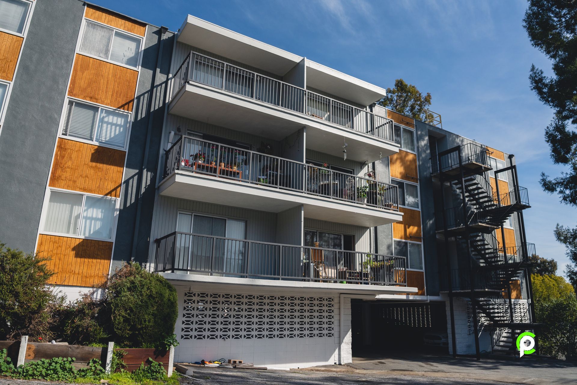 Apartment building exterior with balconies and a fire escape, grey and orange facade.