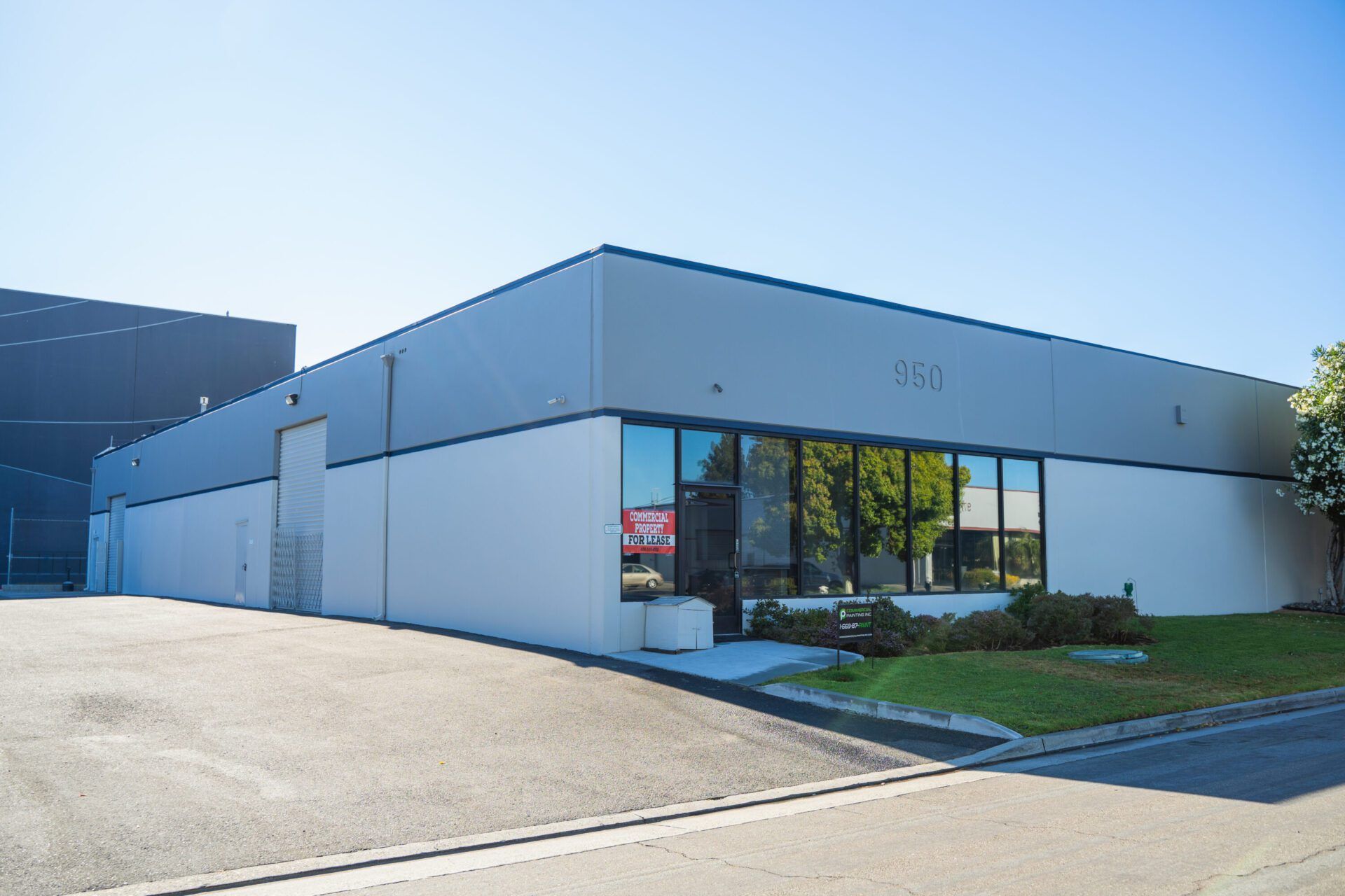 A large white building with a lot of windows is sitting on the side of the road.