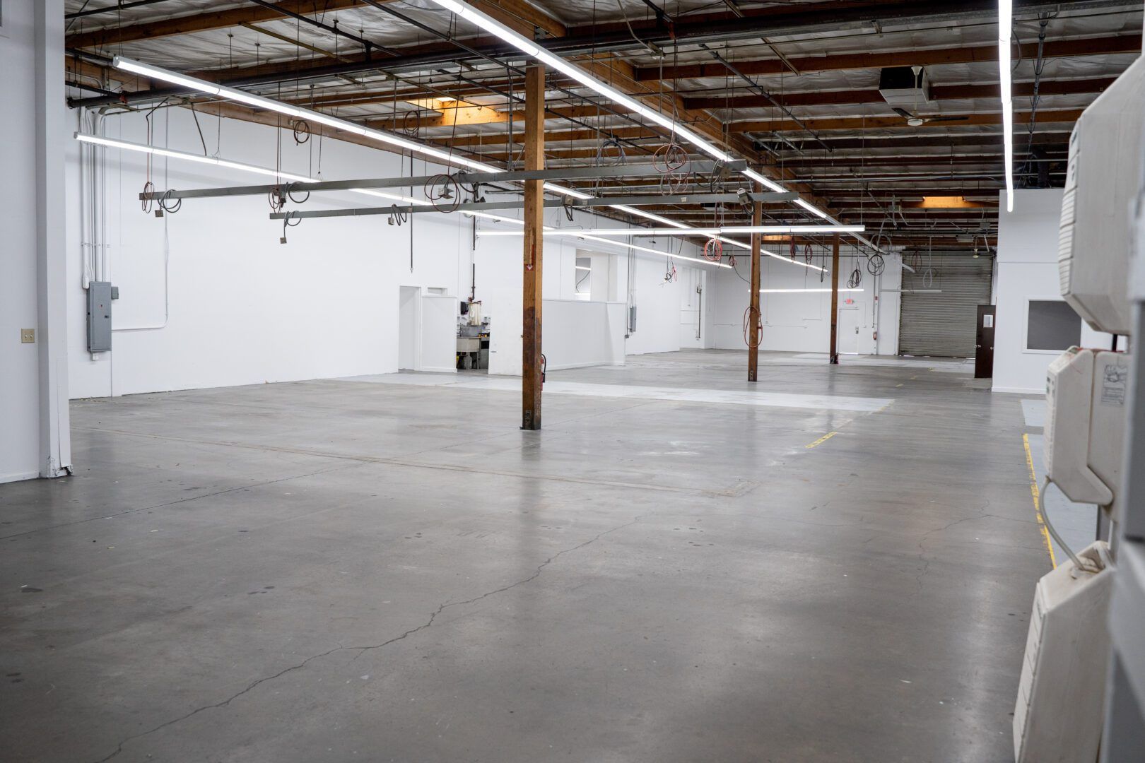 A large empty warehouse with white walls and a concrete floor.