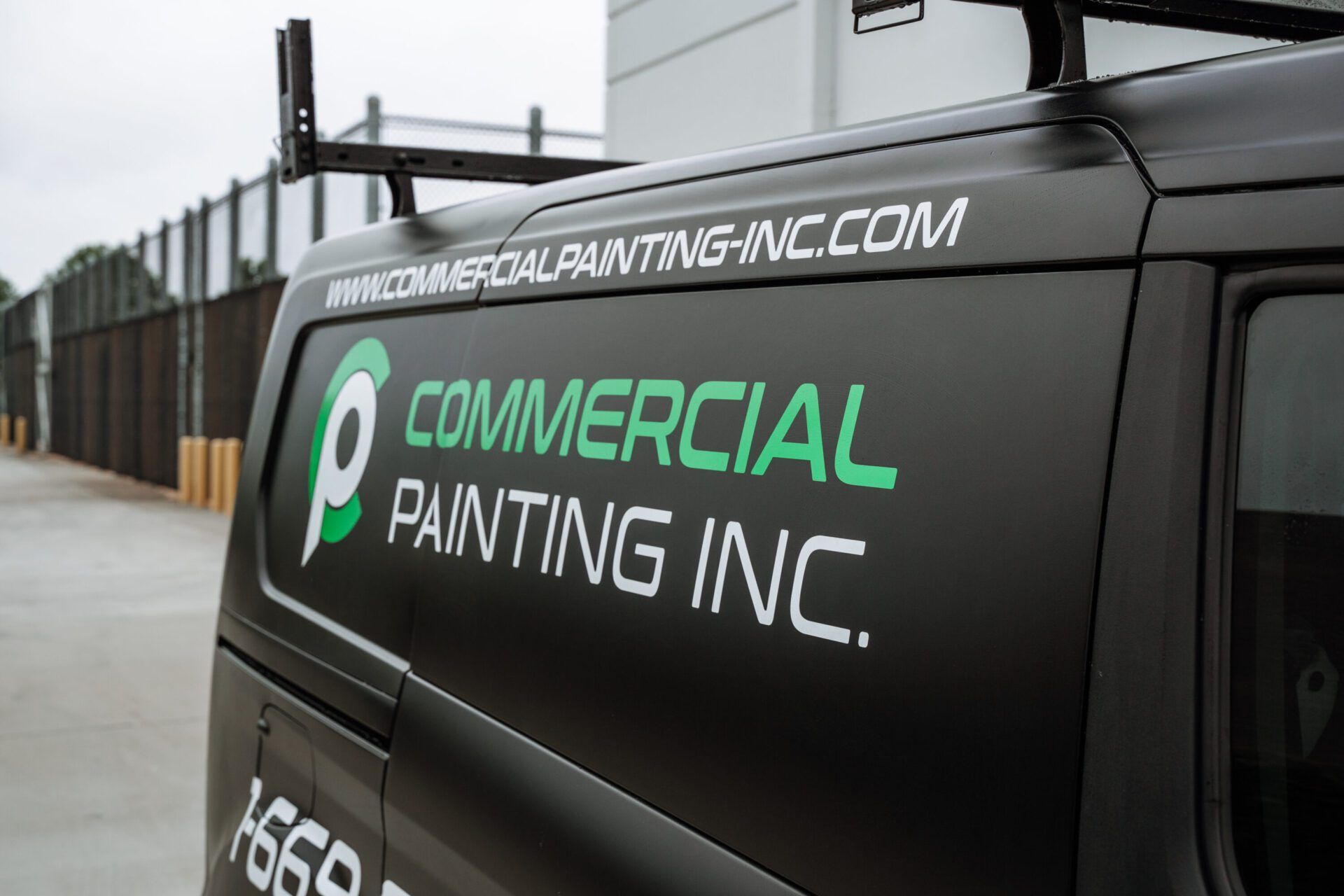 A black commercial painting inc. van is parked in a parking lot.
